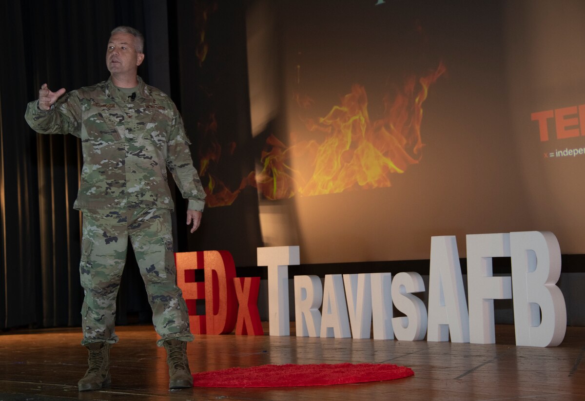 An Airman speaks on a stage.
