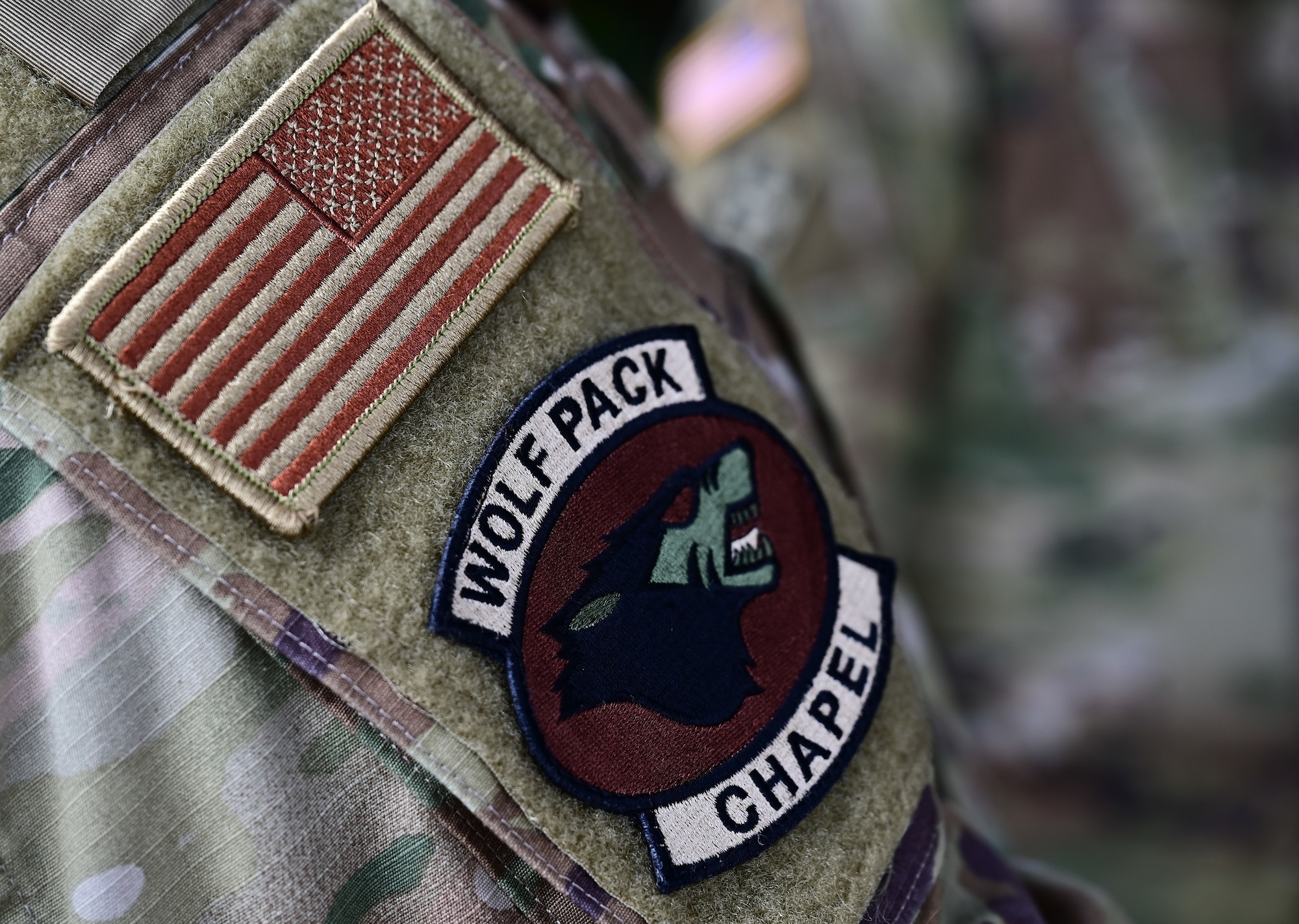 A U.S. Air Force chaplain’s assistant displays the “Wolf Pack” Chapel Corps morale patch during the inaugural Clergy Day at Kunsan Air Base, Republic of Korea, Nov. 8, 2022. The chapel assists with service members’ spiritual wellbeing, one of the core Comprehensive Airman’s Fitness pillars that help keep Airmen fit-to-fight. (U.S. Air Force photo by Staff Sgt. Sadie Colbert)