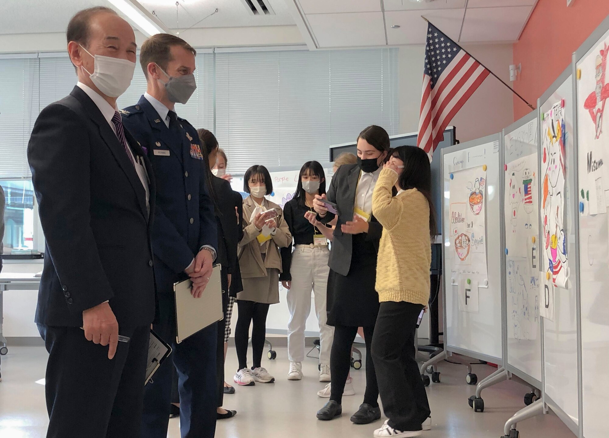 Members look at mascots made by students on a white board.