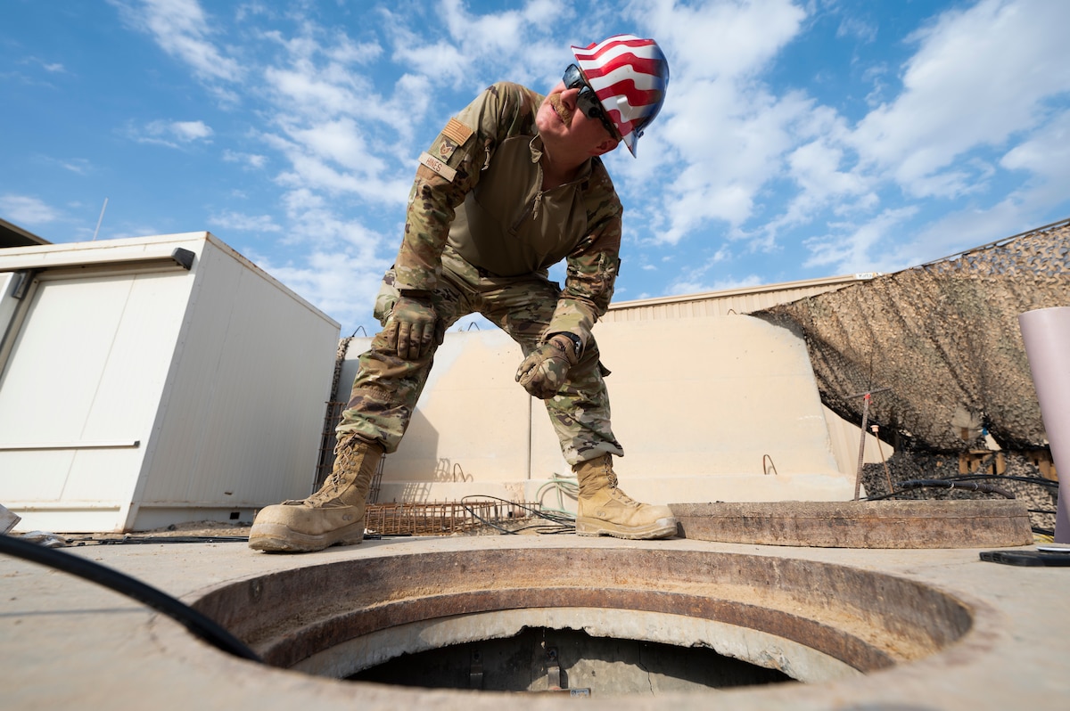 U.S. Air Force Tech. Sgt. John Hines, 386th Expeditionary Communications Squadron cable and antenna systems NCOIC, coordinates with a teammate at another manhole in order to determine when to pull new cable through at Ali Al Salem Air Base, Kuwait, Nov. 3, 2022. Hundreds of feet of new cable had to be rerouted in order to maximize new construction space while maintaining communication capabilities for multiple geographically separated units. (U.S. Air Force photo by Staff Sgt. Dalton Williams)