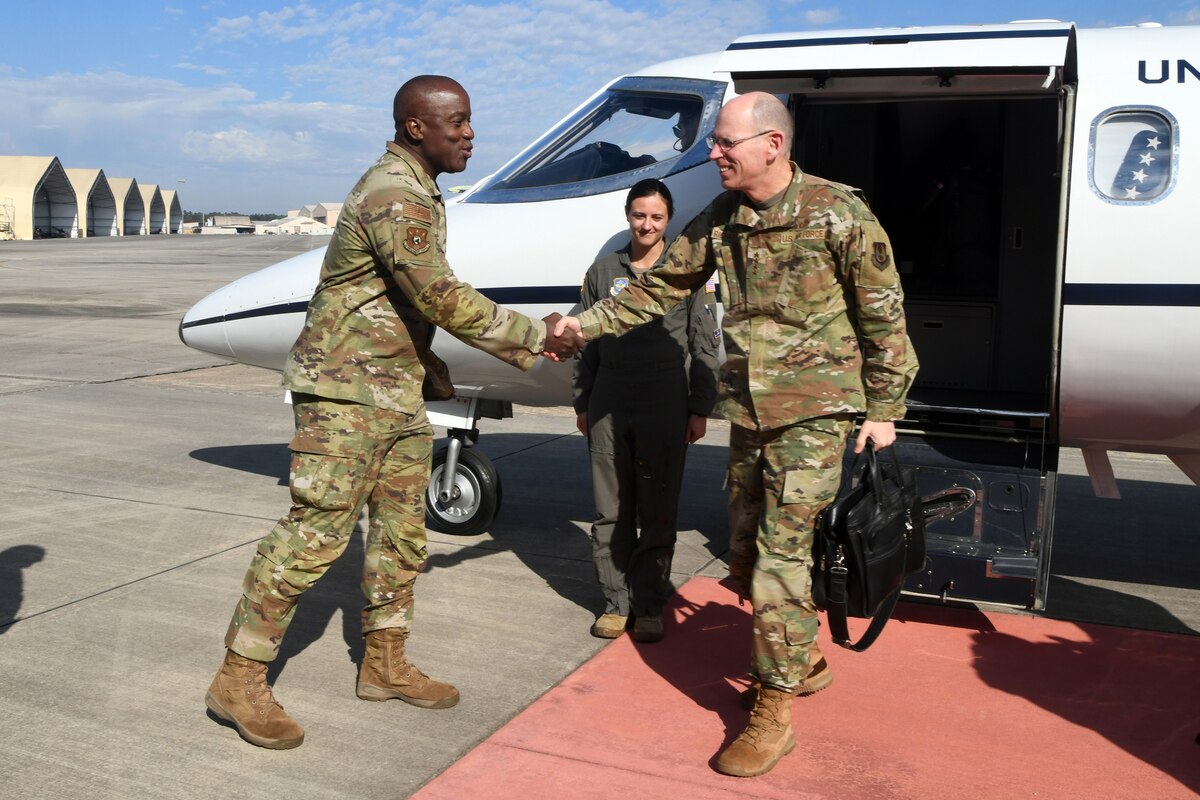 Photo shows two people shaking hands outside aircraft