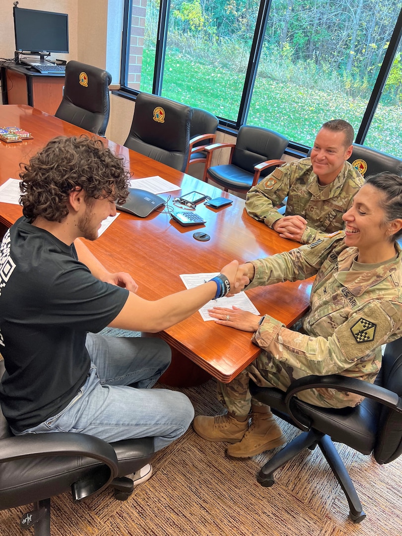 Jordan Page (left) shares a congratulatory handshake with U.S. Army Col. Janelle Kutter, commander, Eastern Sector (center) after signing his U.S. Air Force Contract. U.S. Air Force Chief Master Sgt. Michael Page, Eastern Sector senior enlisted advisor, and Jordan's father (right) watched as his son completed his one-day processing at Milwaukee MEPS, one of the 34 MEPS he serves as SEA.