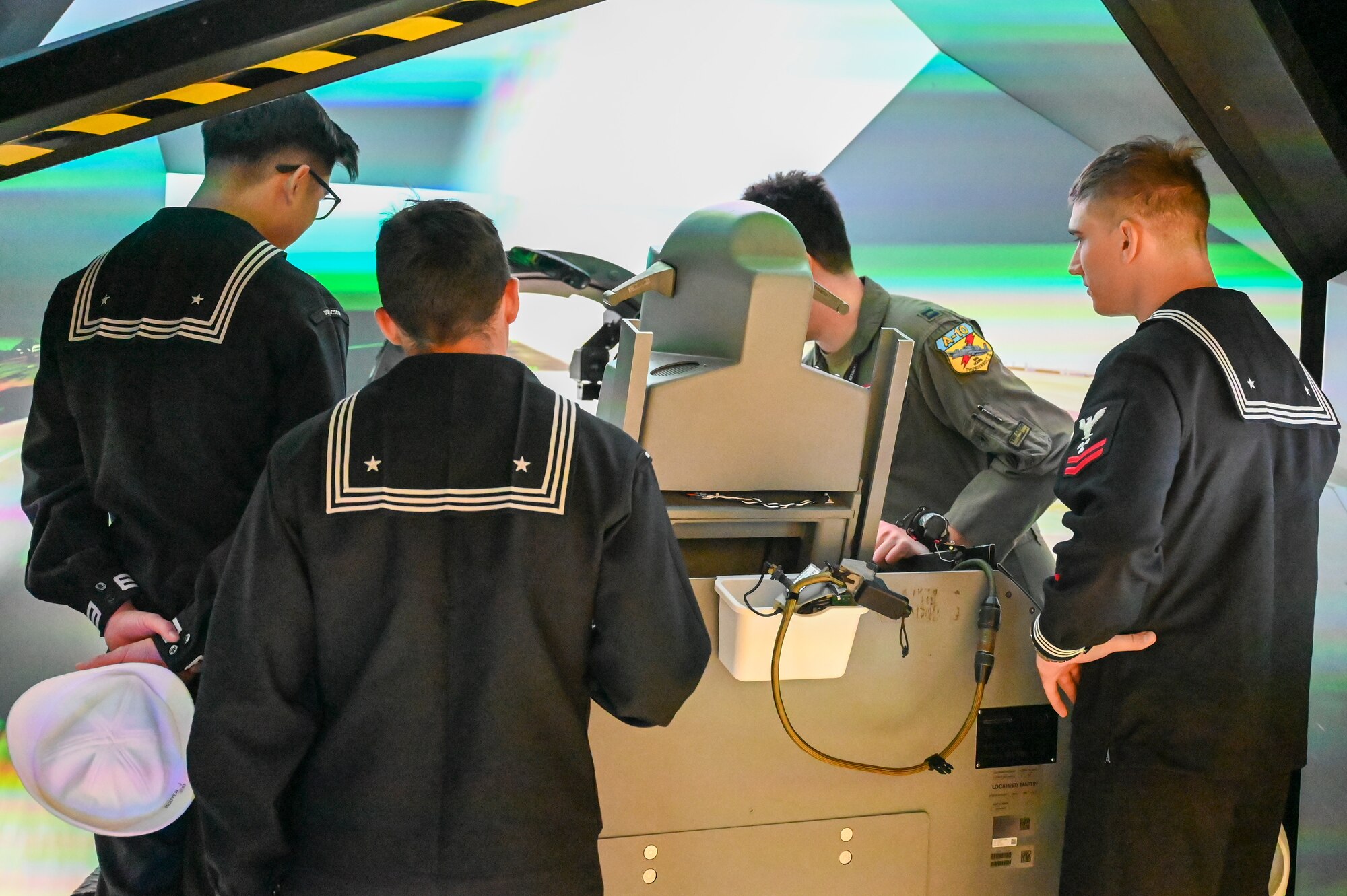 A photo of Navy members looking at an A-10 simulator.