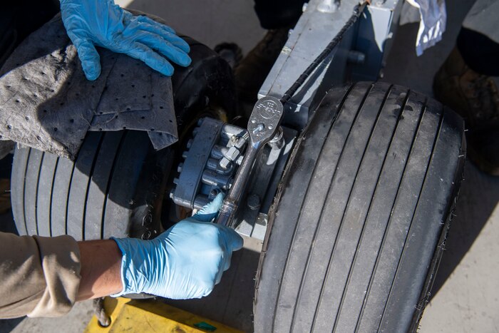 U.S. Air Force Airmen from the 31st Maintenance Squadron Aerospace Ground Equipment bomb lift section, bleed a hydraulic brake caliper at Aviano Air Base, Italy, Nov. 8, 2022. The 31st MXS AGE machinery is used on the flight-line, in back shops and the rest of base. (U.S. Air Force photo by Airman 1st Class Thomas Calopedis)