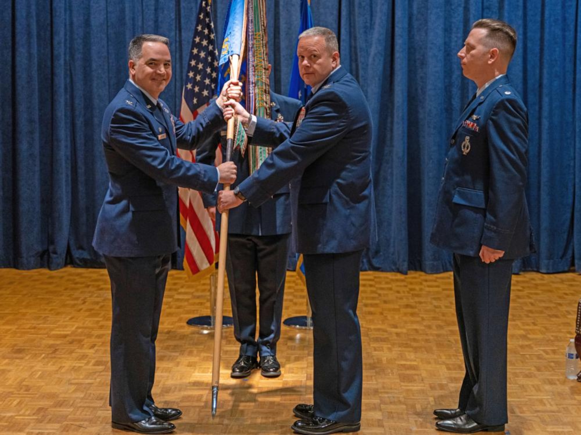 Col. Jason Vattioni (left), 377th Air Base Wing commander, accepts the 576th Flight Test Squadron guidon from Col. Christopher Cruise (center), outgoing commander 576FLTS, during a Change of Command ceremony November 8, 2022 at Vandenberg Space Force Base, Californis as Lt. Col. Tony Santino looks on. (Photo by MSgt Guy McCutcheon, 576 FLTS)