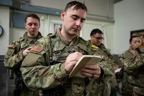 Spc. Devin Greenway, a military policeman with Company A, 49th Missile Defense Battalion, takes notes from the prior shift through a changeover during Exercise Guardian Watch at Fort Greely, Alaska, Nov. 1, 2022. Guardian Watch 23 focused on conducting ground-based midcourse Defense and critical installations security, which are the two missions of the 49th Missile Defense Battalion. (Alaska National Guard photo by Staff Sgt. Katie Mazos-Vega)