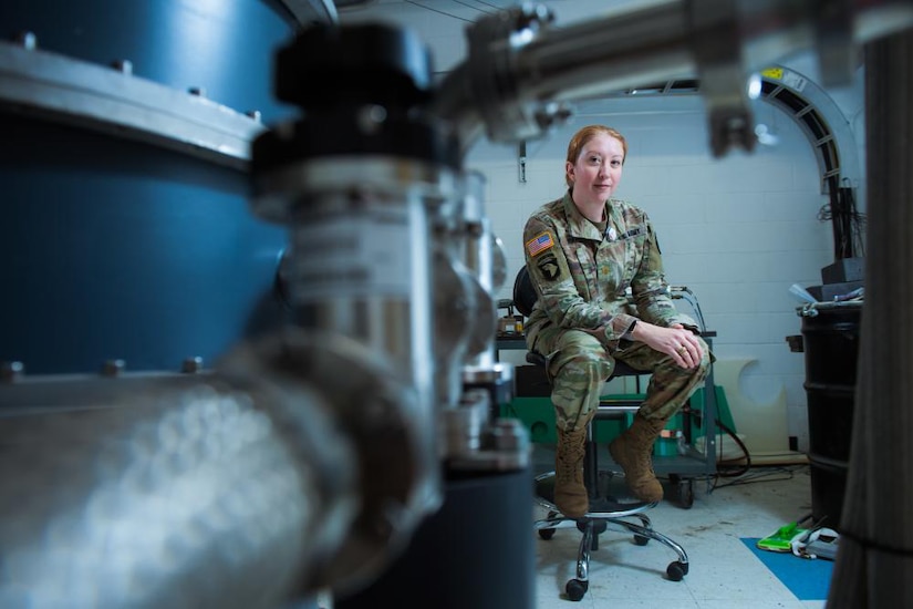 A woman in uniform sits in a laboratory.