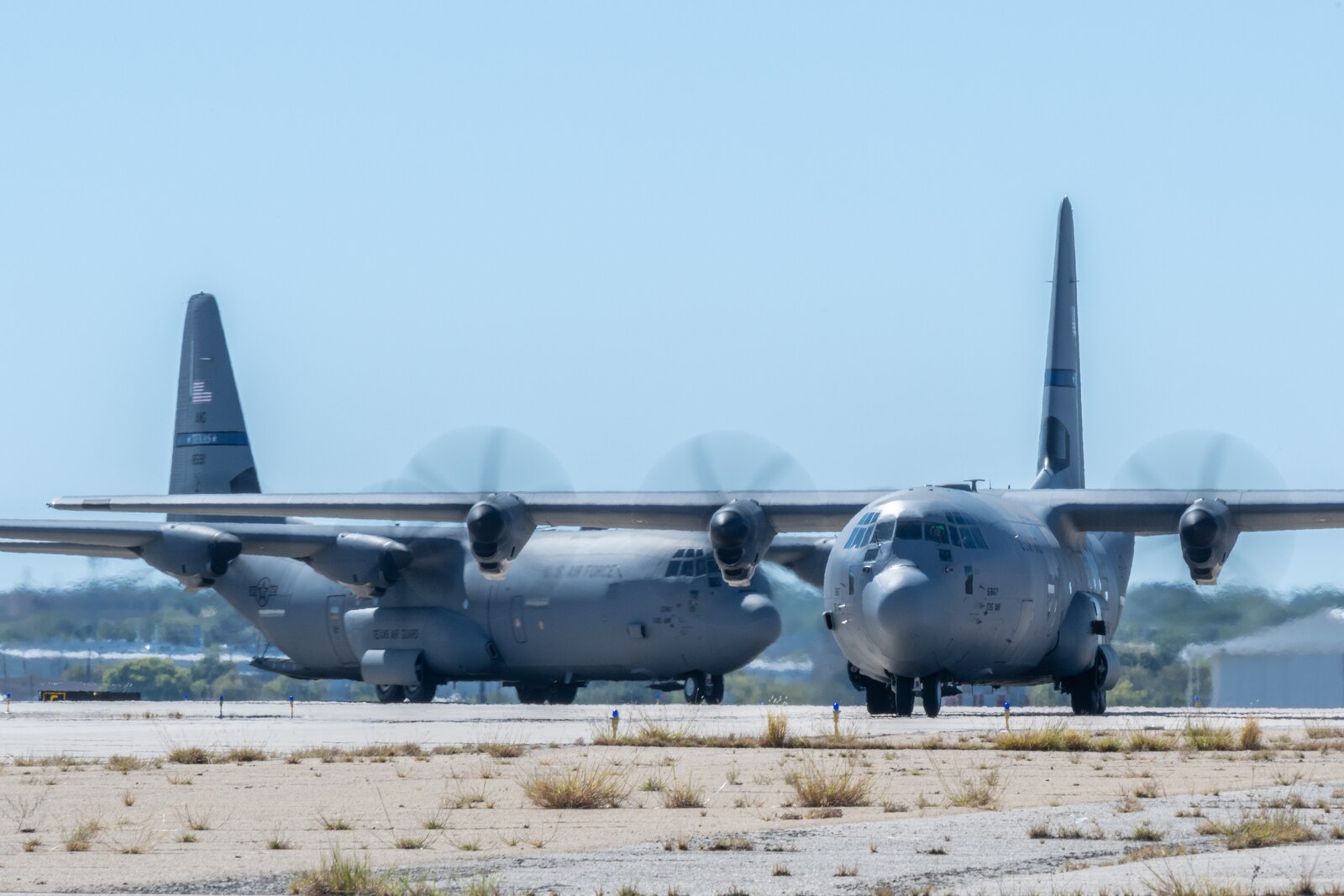 Two C-130Js taxi on runway.