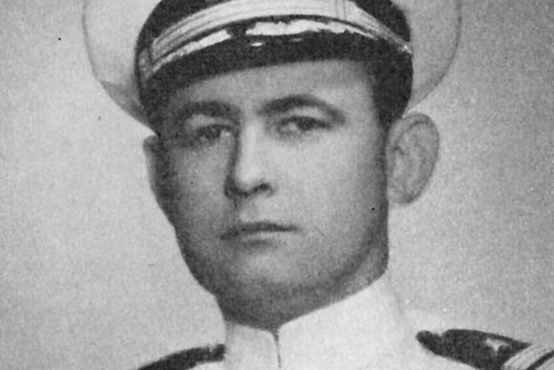 A man in a white uniform and cap poses for a photo.