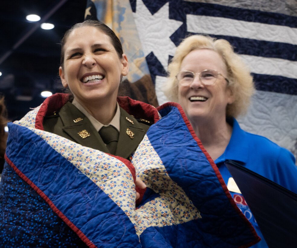 Col. Tina L. Kirkpatrick (left), commander, commander, 475th Quartermaster Group, expresses her gratitude to members of Quilts of Valor during the International Quilting Festival in Houston Nov. 3, 2022. Kirkpatrick was invited to the festival by senior leaders of Quilts of Valor so they could present a custom quilt designed by Leo McClure, one of more than 10,000 Quilts of Valor members. Kirkpatrick, who also serves as the suicide prevention program manager for the 75th Innovation Command, plans to collaborate with Quilts of Valor, a national organization that has made more than 300,000 quilts designed specifically for veterans in honor of their service and sacrifice, to integrate quilting as a form of art therapy to enhance Soldier resiliency. (U.S. Army photo by Staff Sgt. John L. Carkeet IV, 75th Innovation Command).