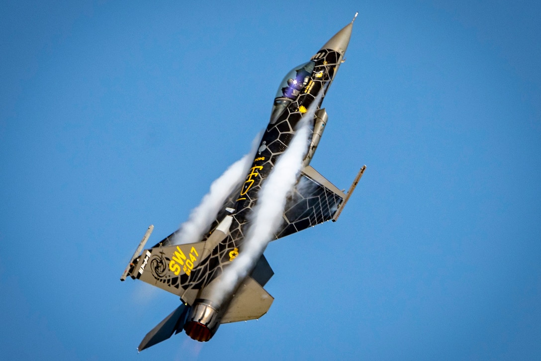 An aircraft emits smoke while flying vertically during an aerial maneuver