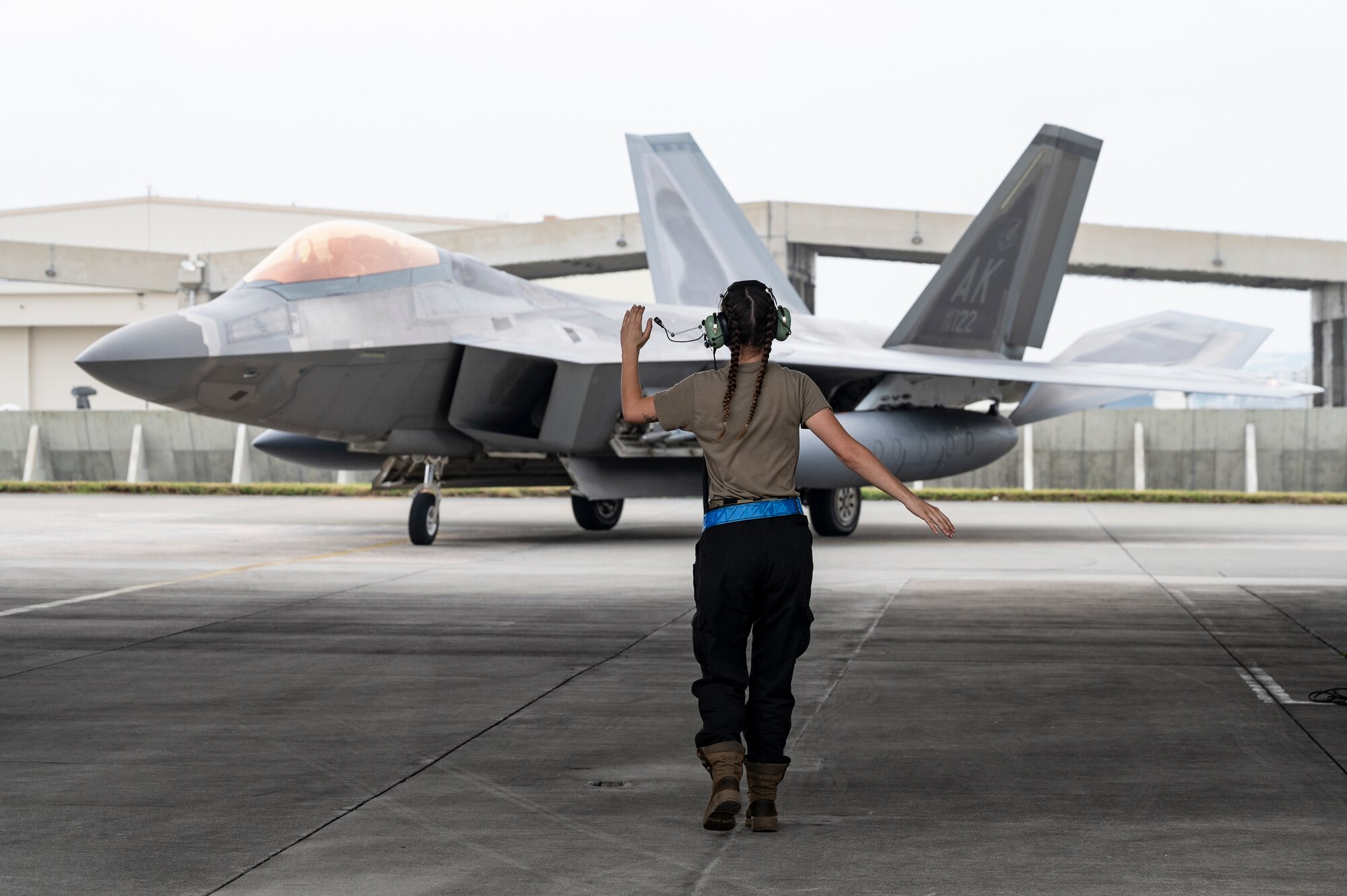 Airman 1st Class Carly Selitto, 3rd Aircraft Maintenance Squadron crew chief, marshals a 525th Fighter Squadron F-22 Raptor as it arrives for a temporary deployment to Kadena Air Base, Japan, Nov. 8, 2022. For decades, Kadena Air Base has served as the keystone of the Pacific. The base's strategic position makes it a vital staging location for forces to deter regional adversaries and project U.S. airpower throughout the Indo-Pacific. (U.S. Air Force photo by Senior Airman Jessi Roth)