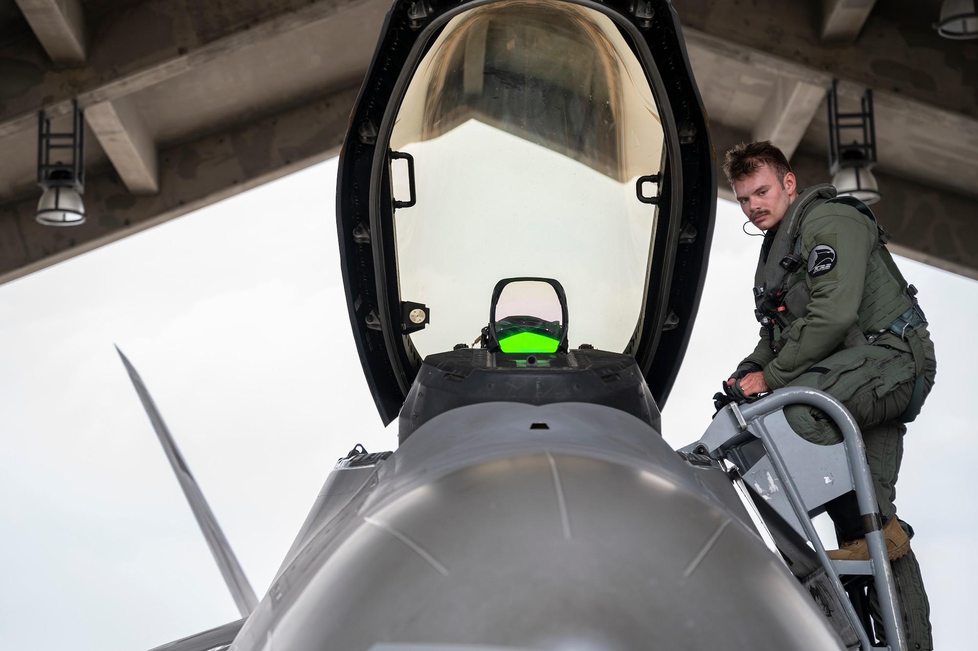 A U.S. Air Force F-22 Raptor pilot assigned to the 525th Fighter Squadron descends from the cockpit after arriving as part of a temporary deployment at Kadena Air Base, Japan, Nov. 8, 2022. The deployment of newer and more advanced aircraft at Kadena exemplifies the Department of Defense's continued commitment to enhancing our posture while building on the strong foundation of our Alliance With Japan. (U.S. Air Force photo by Senior Airman Jessi Roth)