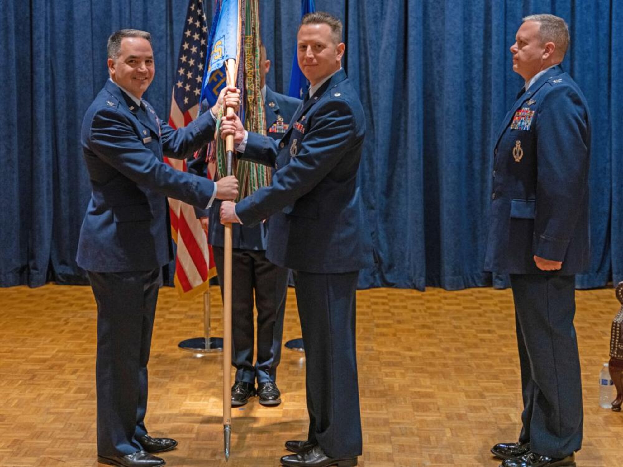 Col. Jason Vattioni (left), 377th Air Base Wing Commander, passes the 576th Flight Test Squadron guidon to Lt. Col. Tony Santino (center), incoming commander 576 FLTS, during a Change of Command ceremony November 8, 2022 at Vandenberg Space Force Base, California as Col. Christopher Cruise (right), outgoing commander 576 FLTS, looks on. (Photo by Guy McCutcheon, 576 FLTS)
