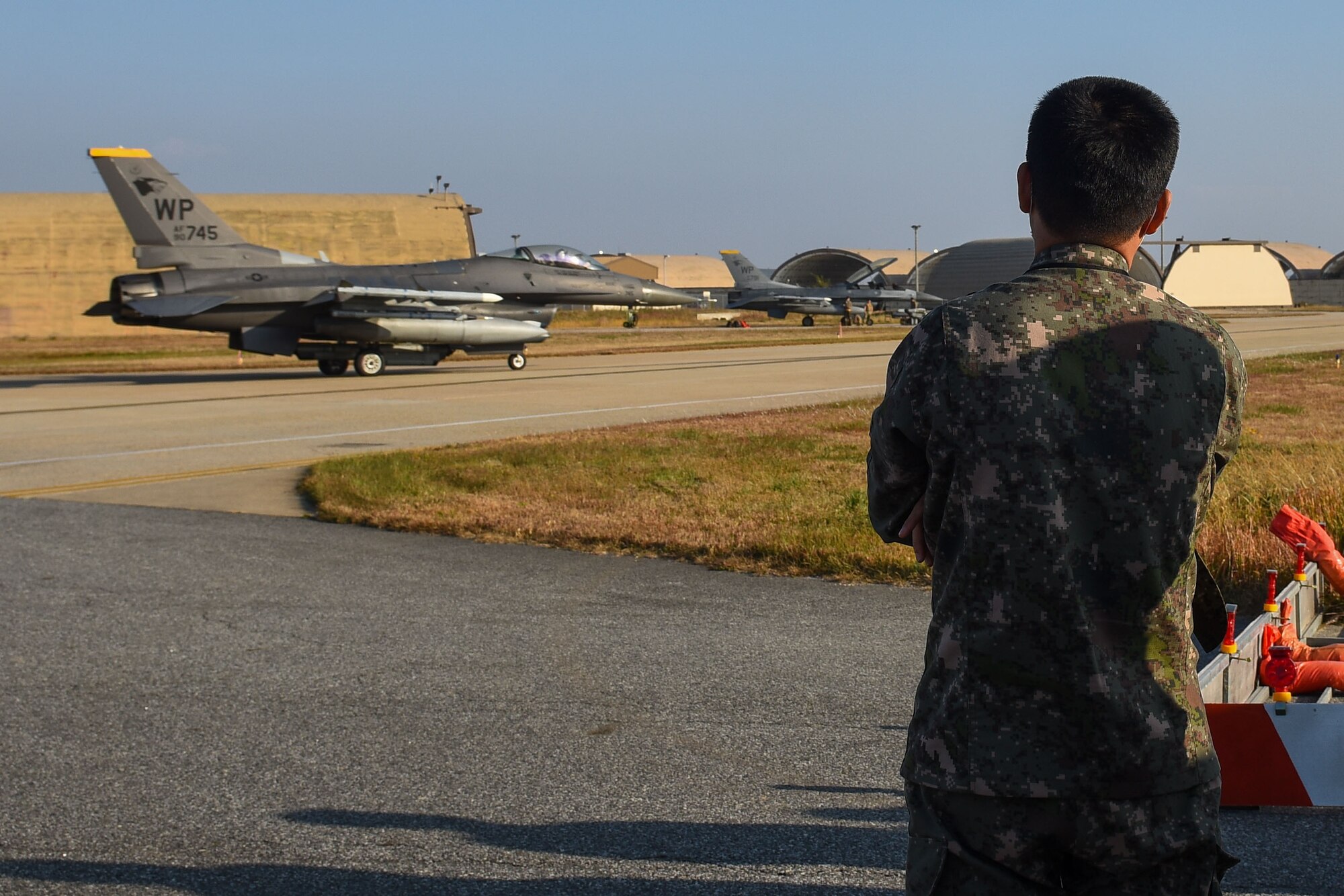 A Republic of Korea Army soldier from the 35th Infantry Division watches an F-16 Fighting Falcon taxi during an 8th Maintenance Group immersion tour at Kunsan Air Base, Republic of Korea, Nov. 8, 2022. For many, this was the first time they saw a U.S. Air Force aircraft up close. (U.S. Air Force photo by Tech. Sgt. Timothy Dischinat)