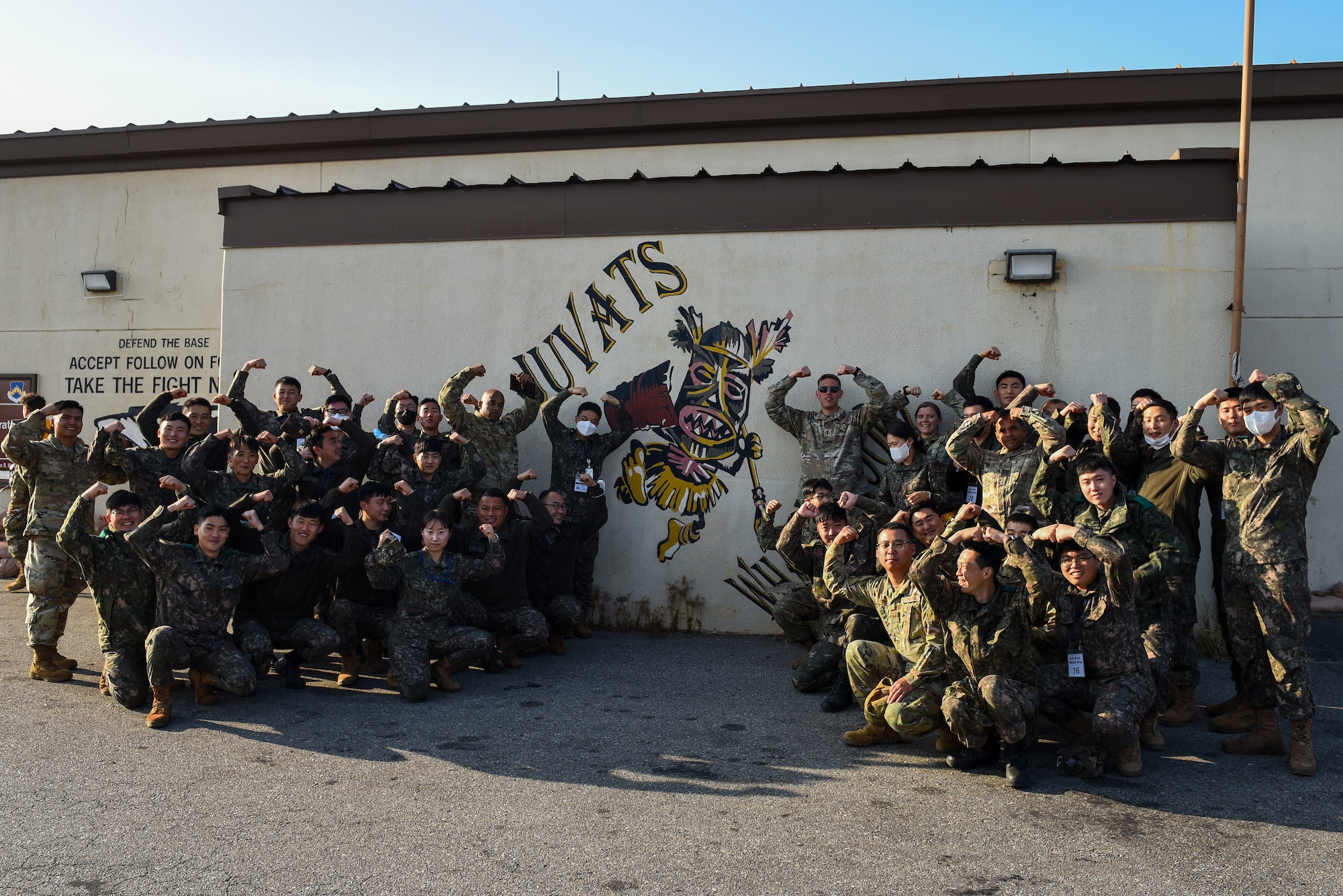 Airmen from the 8th Fighter Wing, Soldiers from  the U.S. Army and Republic of Korea Army 35th Infantry Division pose for a group photo during an 8th Maintenance Group immersion tour at Kunsan Air Base, Republic of Korea, Nov. 8, 2022. The Soldiers and Airmen held their hands above their head to strike the trademark 80th Fighter Squadron Juvats “Crush’em” pose. (U.S. Air Force photo by Tech. Sgt. Timothy Dischinat)