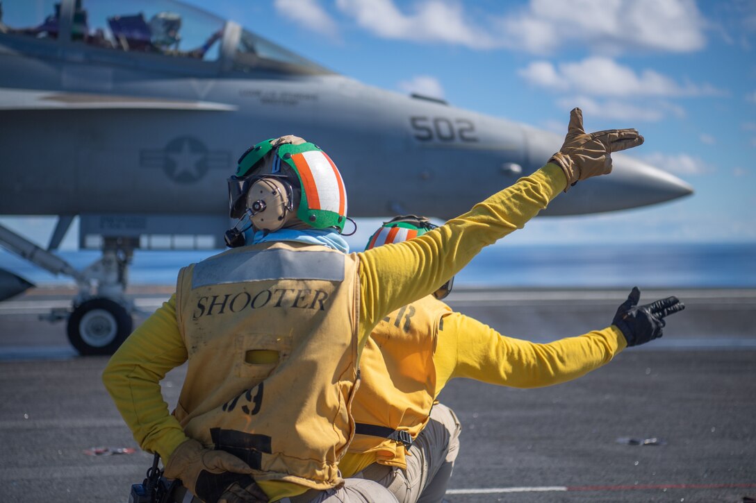 Sailors kneel and point their arms to the right.