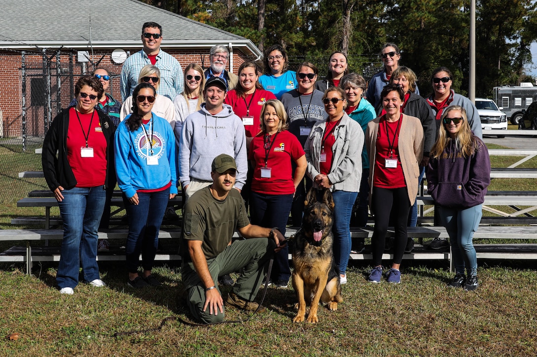 Students of Leadership Carteret pose for a photo with U.S. Marine Corps Cpl. Alex Neuberger (front left), a military working dog handler assigned to Headquarters and Headquarters Squadron, and his dog, Larry, Marine Corps Air Station Cherry Point, North Carolina, Nov. 2, 2022. Leadership Carteret is an annual program run by the Carteret County Chamber of Commerce and gives local leaders, business owners, and professionals knowledge of the economic and social impact of their neighboring Marine Corps installation.