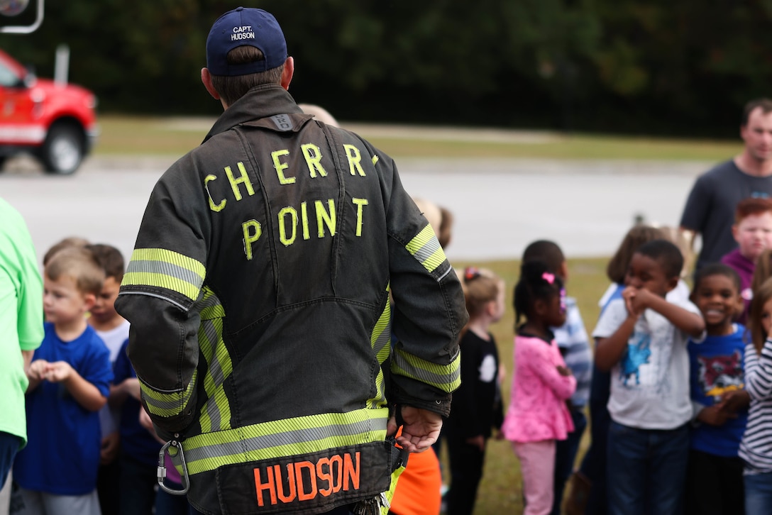 Capt. Edward Hudson, a firefighter with the Cherry Point Fire Department, waits to get a photo with students after showing them Fire Engine 2 at Graham A. Barden Elementary School, Havelock, North Carolina, Oct. 28, 2022. Members of the Cherry Point Fire Department taught students about fire safety and displayed the various tools and equipment firefighters use while fighting fires. (U.S. Marine Corps photo by Lance Cpl. Matthew Williams)
