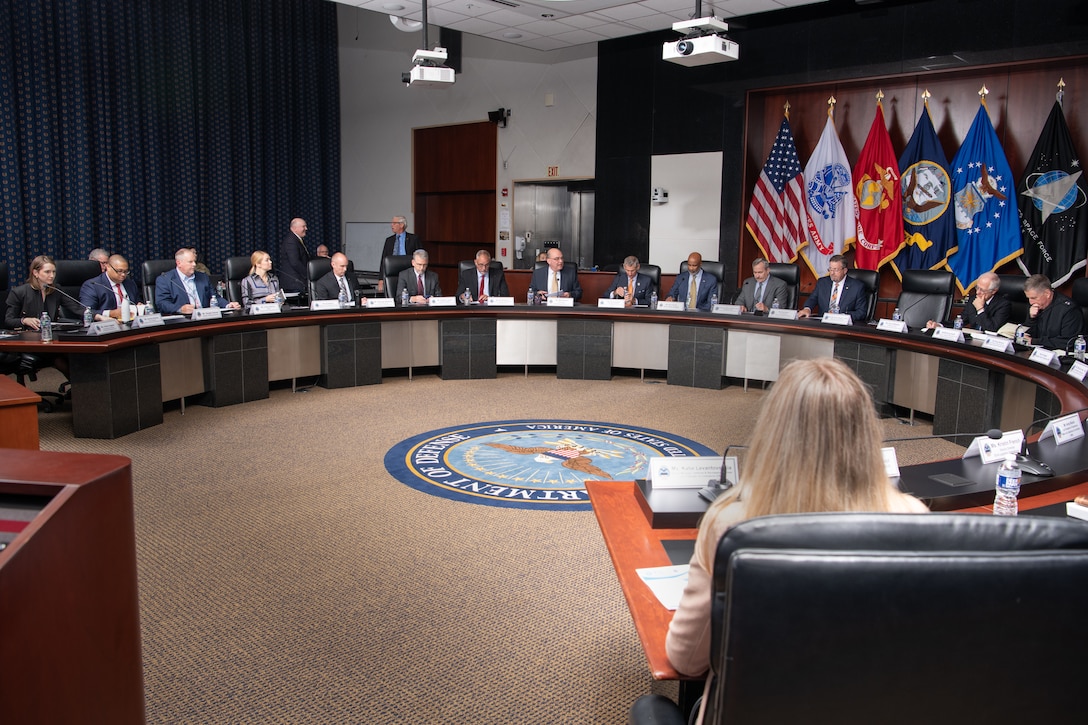 A group of people gather in a room for a meeting.