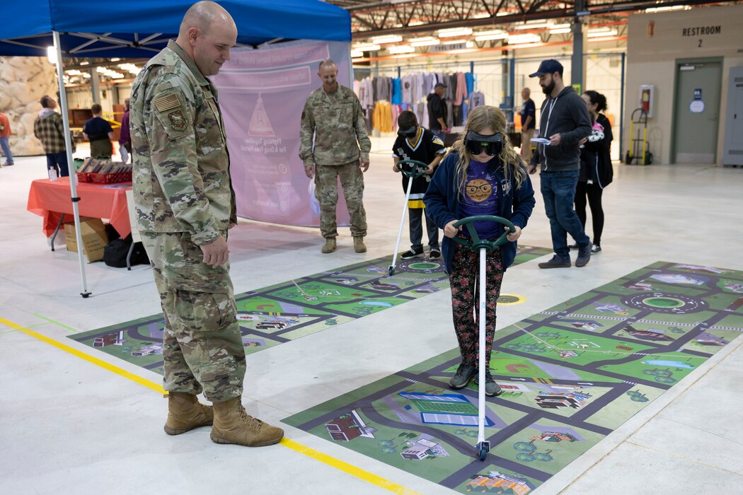 U.S. Air Force Master Sgt. Travis Sites watches as a student navigates a map on a floor mat while wearing alcohol impairment googles as part of Family STEM Night at the former Sino Swearingen hangar at Eastern West Virginia Regional Airport, October 26, 2022. The event was co-hosted by STARBASE Martinsburg and the Air National Guard’s Drug Demand Reduction Program, in honor of Red Ribbon Week.