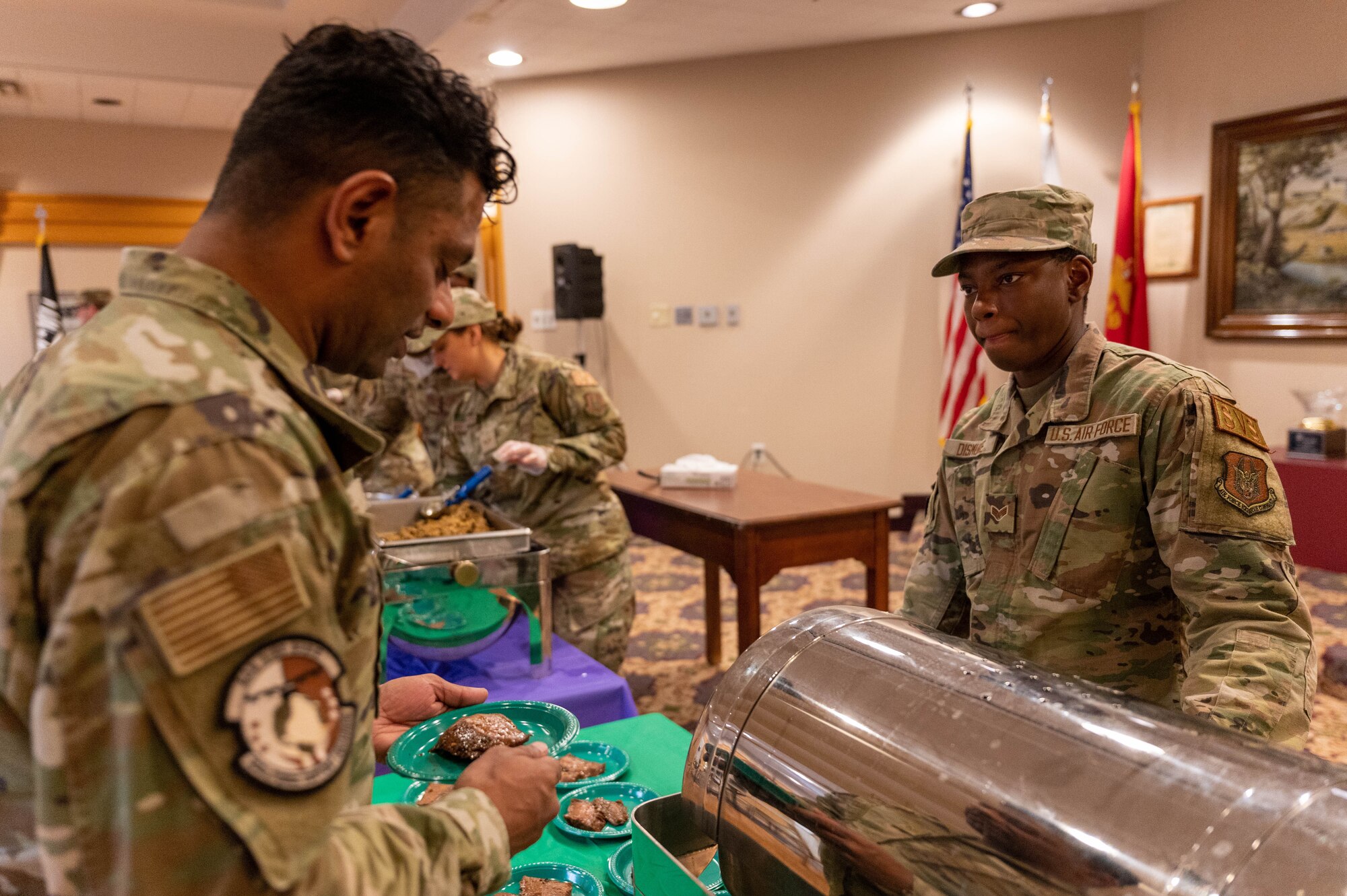 Staff Sgt. Gerrard Perera, left, 934th Force Support Squadron fitness center noncommissioned officer, receives a flank steak from, Senior Airmen Khadesa Dismuke, right, 934th Force Support Squadron services specialist, during the 934th Airlift Wing’s Celebration of Nations at Minneapolis-Saint Paul Air Reserve Station, Minnesota, Nov. 5, 2022. This event provided Airmen an opportunity to try culturally different foods, listen to different music and look at different types of clothes.  (U.S. Air Force photo by Airman First Class Colten Tessness)