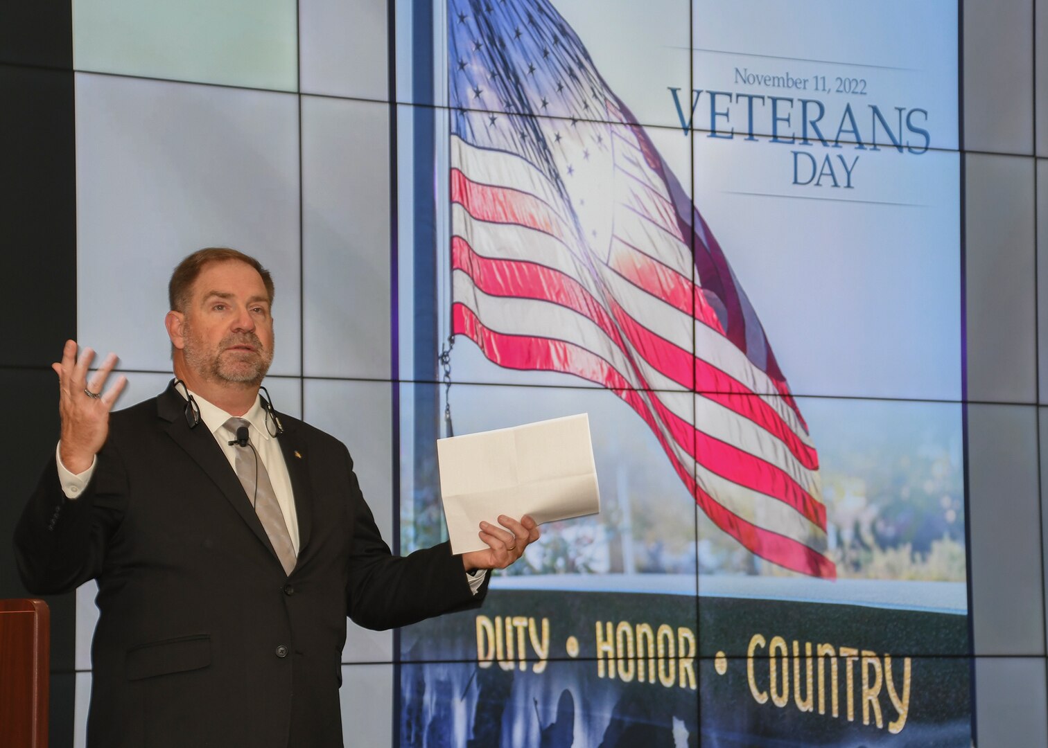 Mike Cannon stands with his hands lifted with a flag behind him