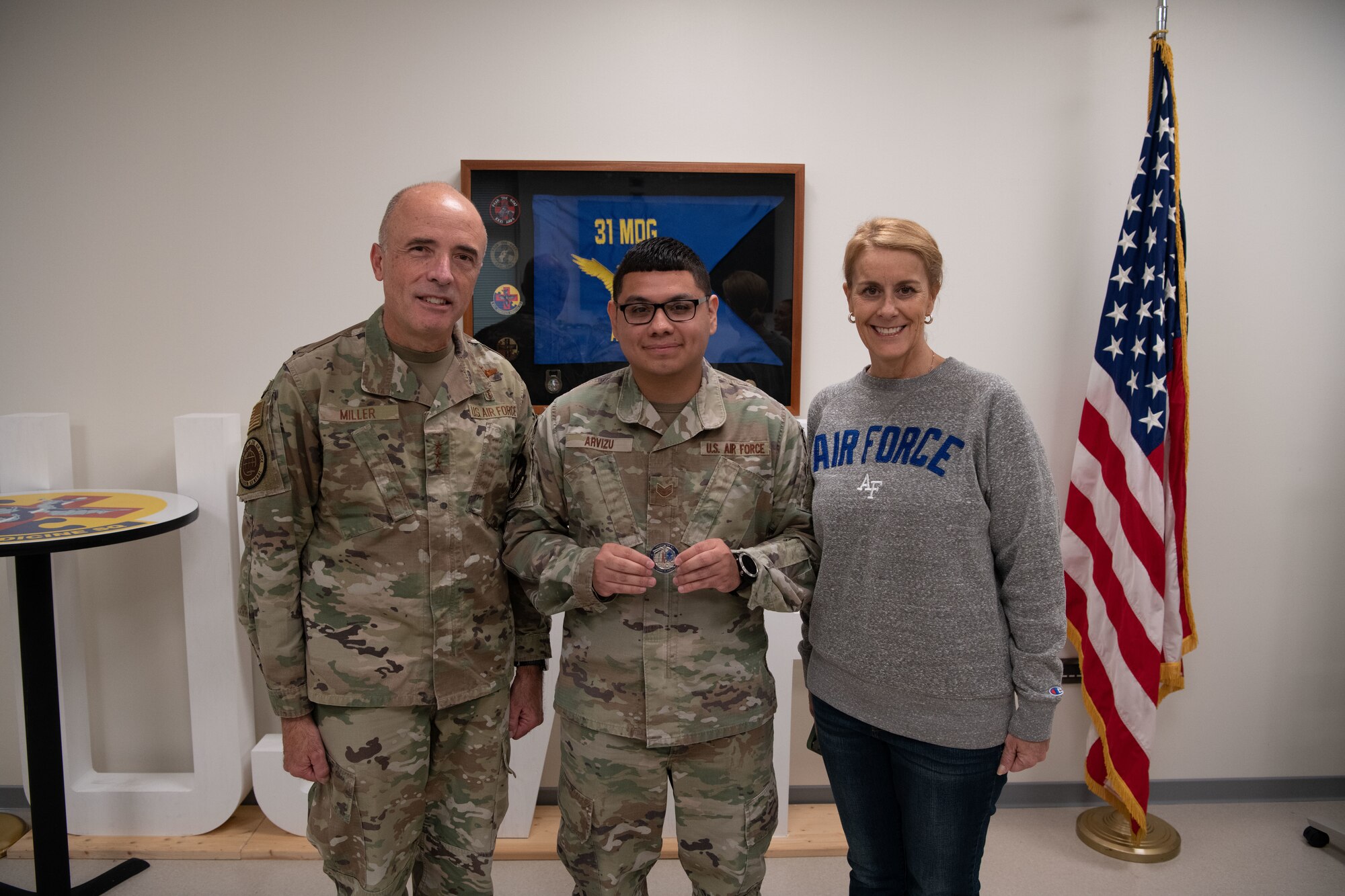 221109-F-QI825-1063
U.S. Air Force Lt. Gen. Robert Miller, Surgeon General of the Air Force, and Chief Master Sgt. Dawn Kolczynski, Medical Enlisted Force and Enlisted Corps Chief, coin U.S. Air Force Staff Sgt. Fernando Arvizu, 31st Operational Medical Readiness Squadron flight medicine administrator, during his visit at Aviano Air Base, Italy, Nov. 9, 2022. Arvizu increased access to care by heping with the coordination of 16 schedules across five clinics for nine providers. During mass deployment lines he led five 4As to execute the administrative support to clear 150 members in less than 24 hours. (U.S. Air Force photo by Airman 1st Class Thomas Calopedis)