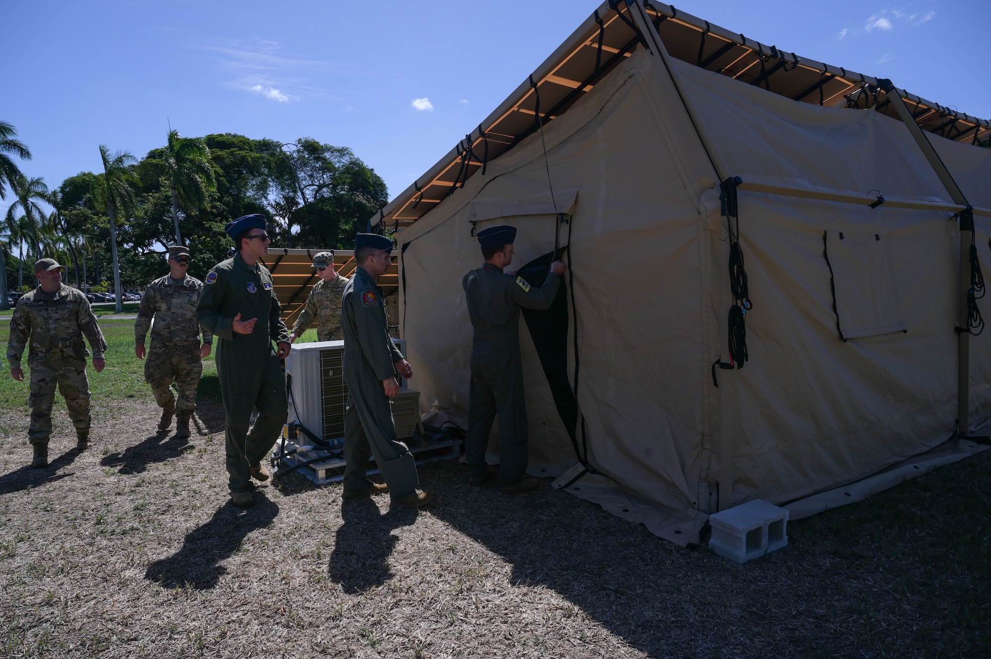 Members assigned to the 15th Wing Innovation Cell display their recent Agile Combat Employment efforts to U.S. Air Force Lt. Gen. David Nahom, commander of Alaskan NORAD Region, Alaskan Command and 11th Air Force, during a 15th Wing immersion tour on Joint Base Pearl Harbor-Hickam, Hawaii, Oct. 24, 2022. Nahom toured an expeditionary tent equipped with solar panels that has the ability to provide a compact mission operations center needed to complete core, functional and theater-specific requirements crucial to ACE. (U.S. Air Force photo by Staff Sgt. Alan Ricker)