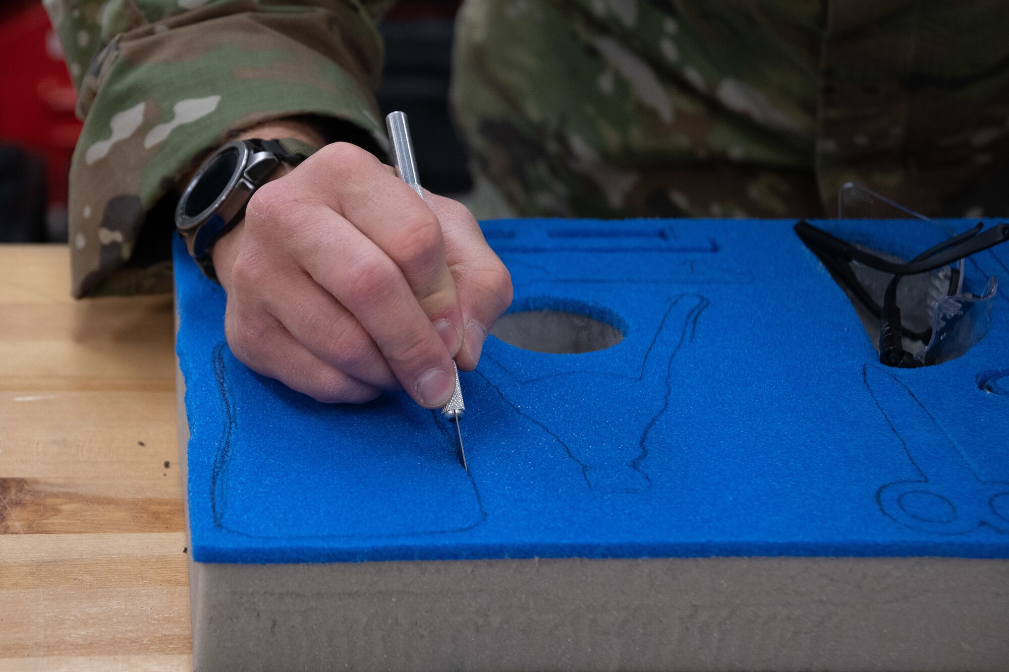 A man cuts into foam to make a spot for a tool.