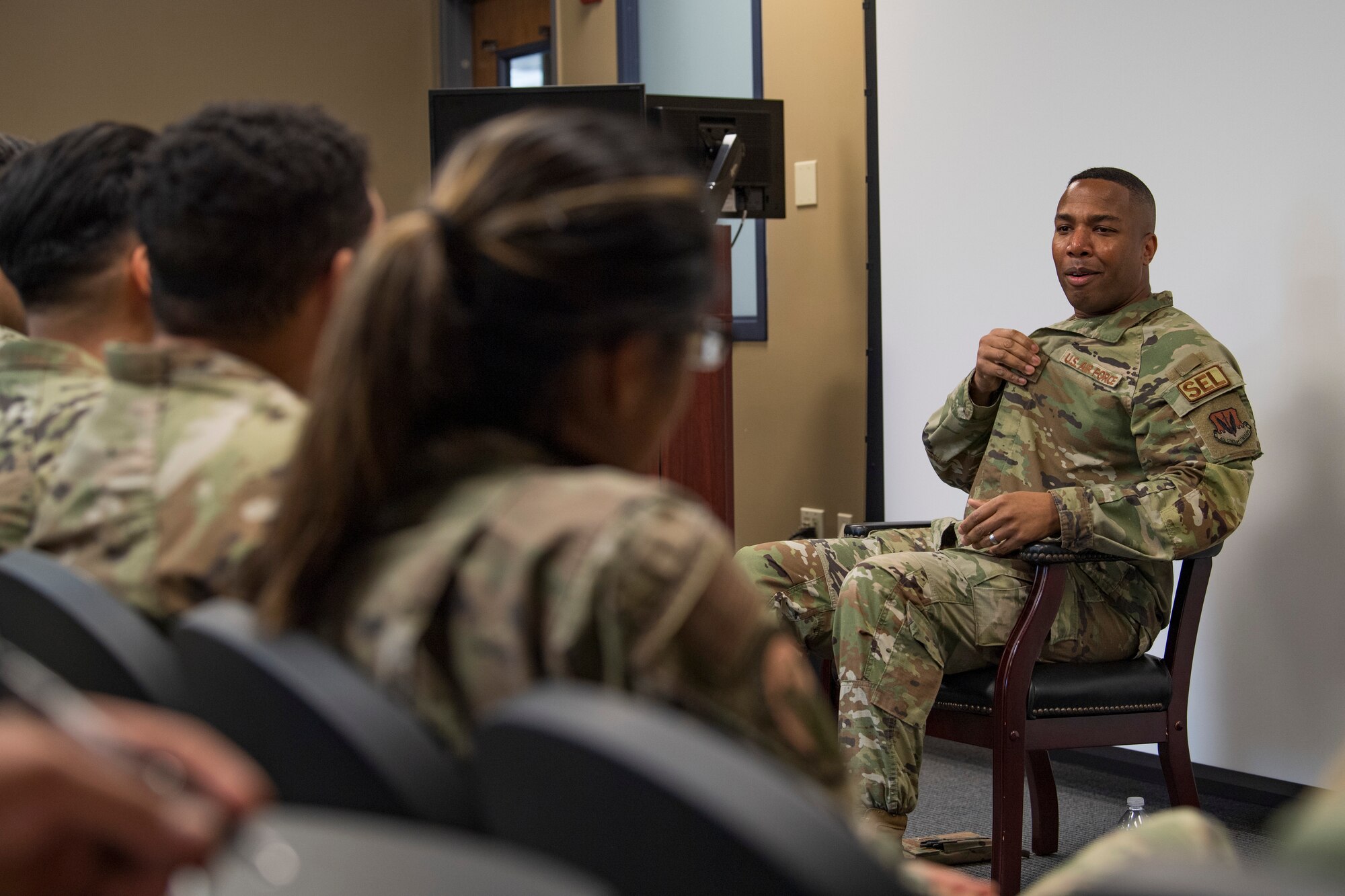 A photo of an Airman speaking while sitting in a chair