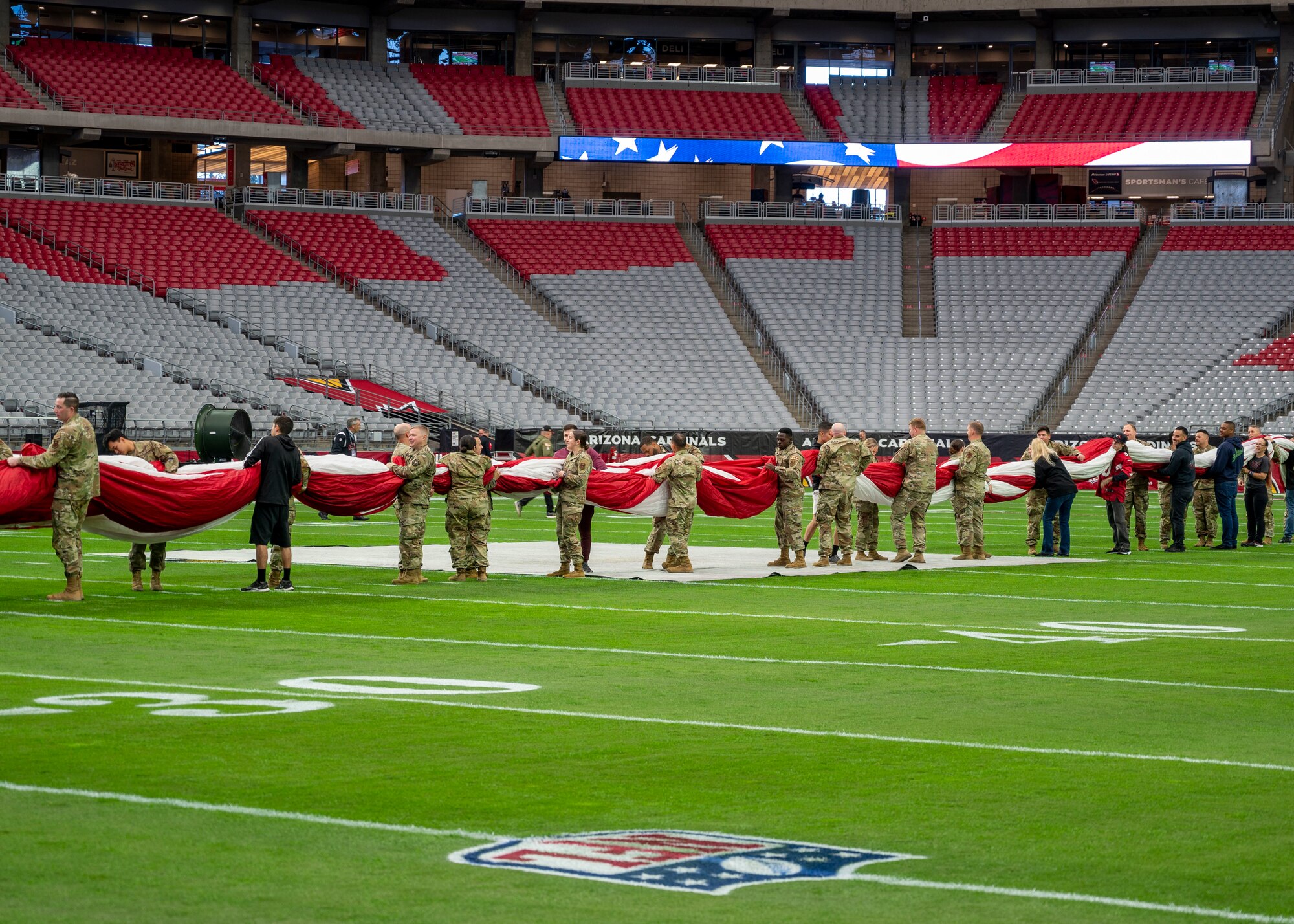 U.S. Air Force Airmen assigned to the 56th Fighter Wing, U.S. Army soldiers assigned to the Phoenix Recruiting Battalion and U.S. Marines practice unfurling the U.S. flag for the Arizona Cardinals Salute to Service event Nov. 6, 2022, at State Farm Stadium, Glendale, Arizona.