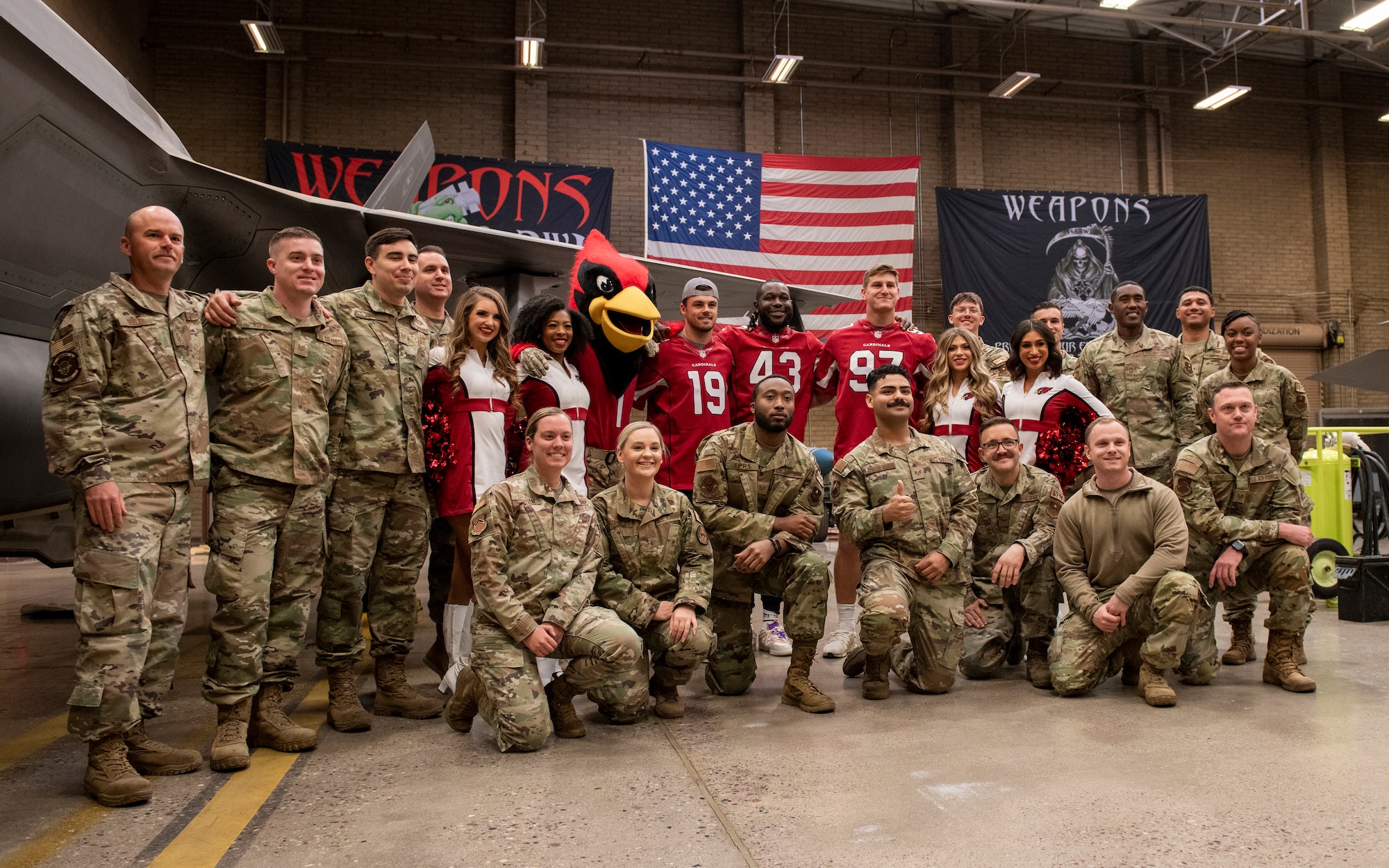Airmen of the 56th Fighter Wing pose for a photo with players, cheerleaders, and the mascot of the Arizona Cardinals Nov. 1, 2022, during a tour of Luke Air Force Base, Arizona.