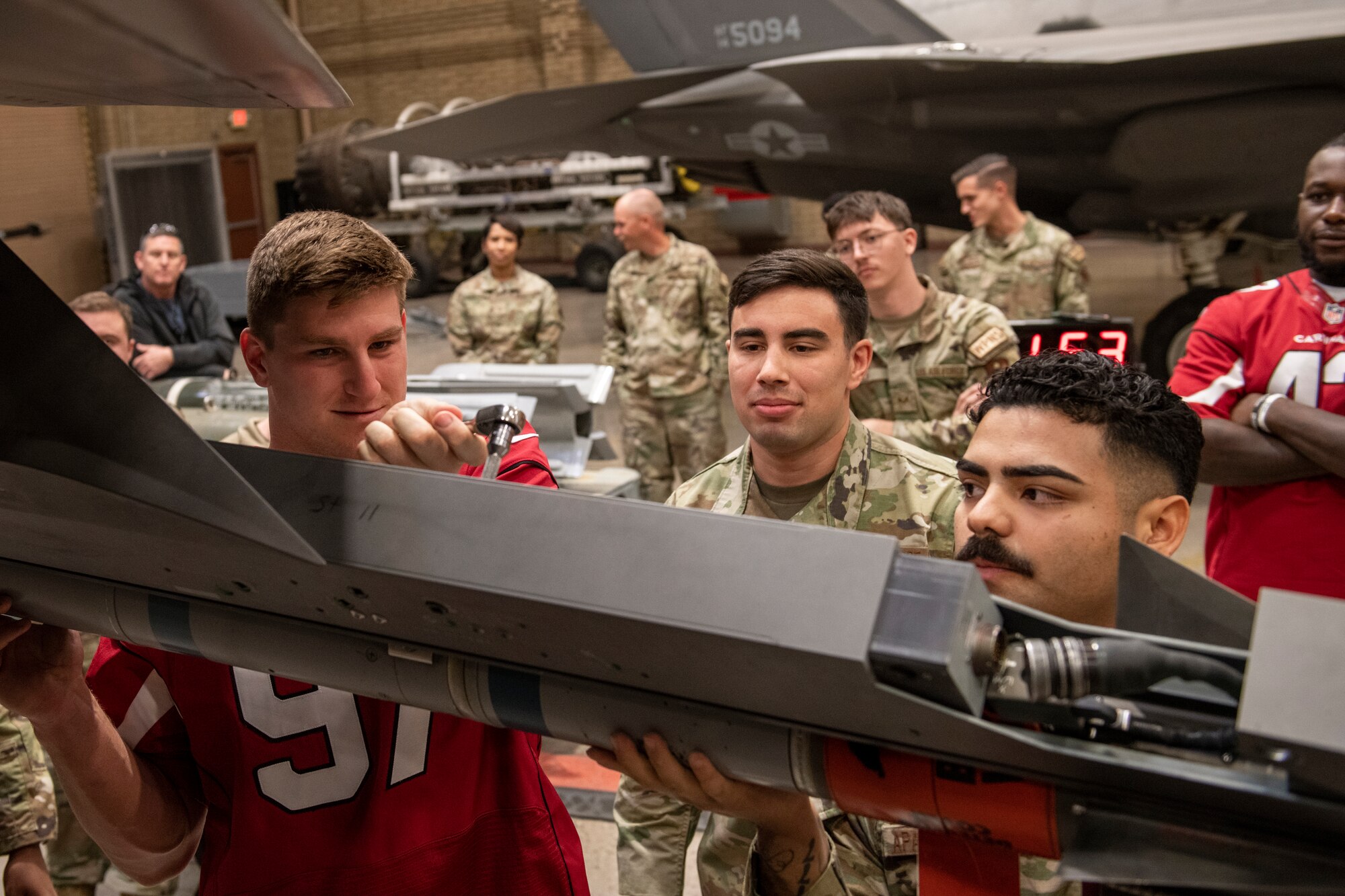 Members of the 56th Component Maintenance Squadron show Cameron Thomas, Arizona Cardinals offensive linebacker, how to attach an Air Intercept Missile 9X to an F-35 Lightning II Nov. 1, 2022, at Luke Air Force Base, Arizona.