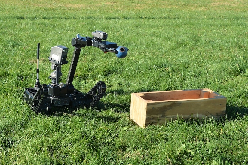 A remotely operated Common Robotic System – Individual uses its extendable arm to drop a simulated grenade into a box during training on Nov. 9, 2022, at Fort Indiantown Gap, Pa. The CRS-I is a 32-pound, tracked robot with multiple cameras and an extendable arm that can fit into a medium ruck sack or an assault pack.