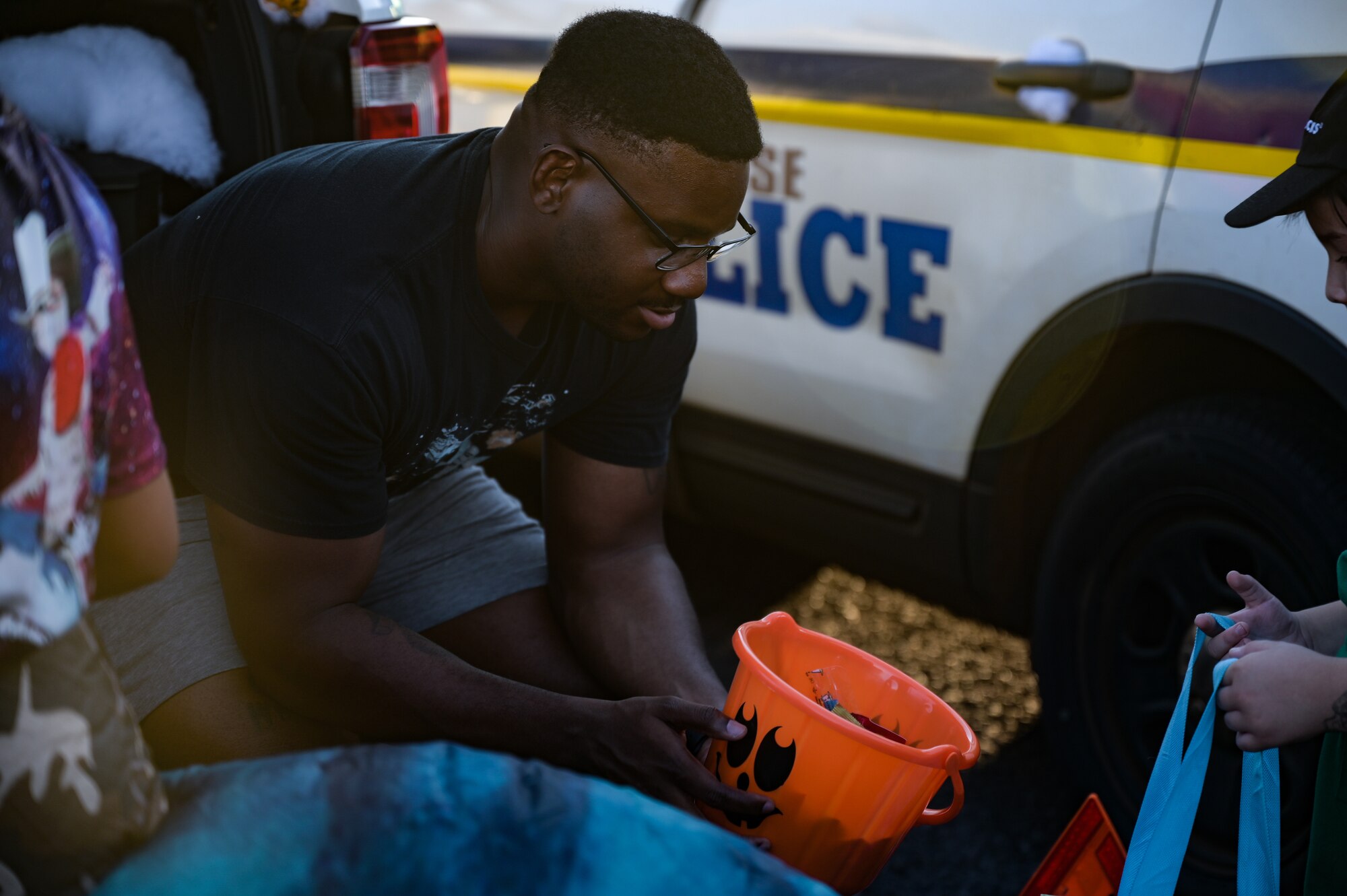 Tech. Sgt. Keshawn Reedus, 647th Security Forces Squadron standardizations and evaluations noncommissioned officer-in-charge, passes out Halloween candy during the Trunks of Treats event at Joint Base Pearl Harbor-Hickam, Hawaii, Oct. 28, 2022. Trunk-or-Treat is an event that offers trick-or-treating down a row of decorated vehicles for families to walk through and receive candy. (U.S. Air Force photo by Staff Sgt. Alan Ricker)