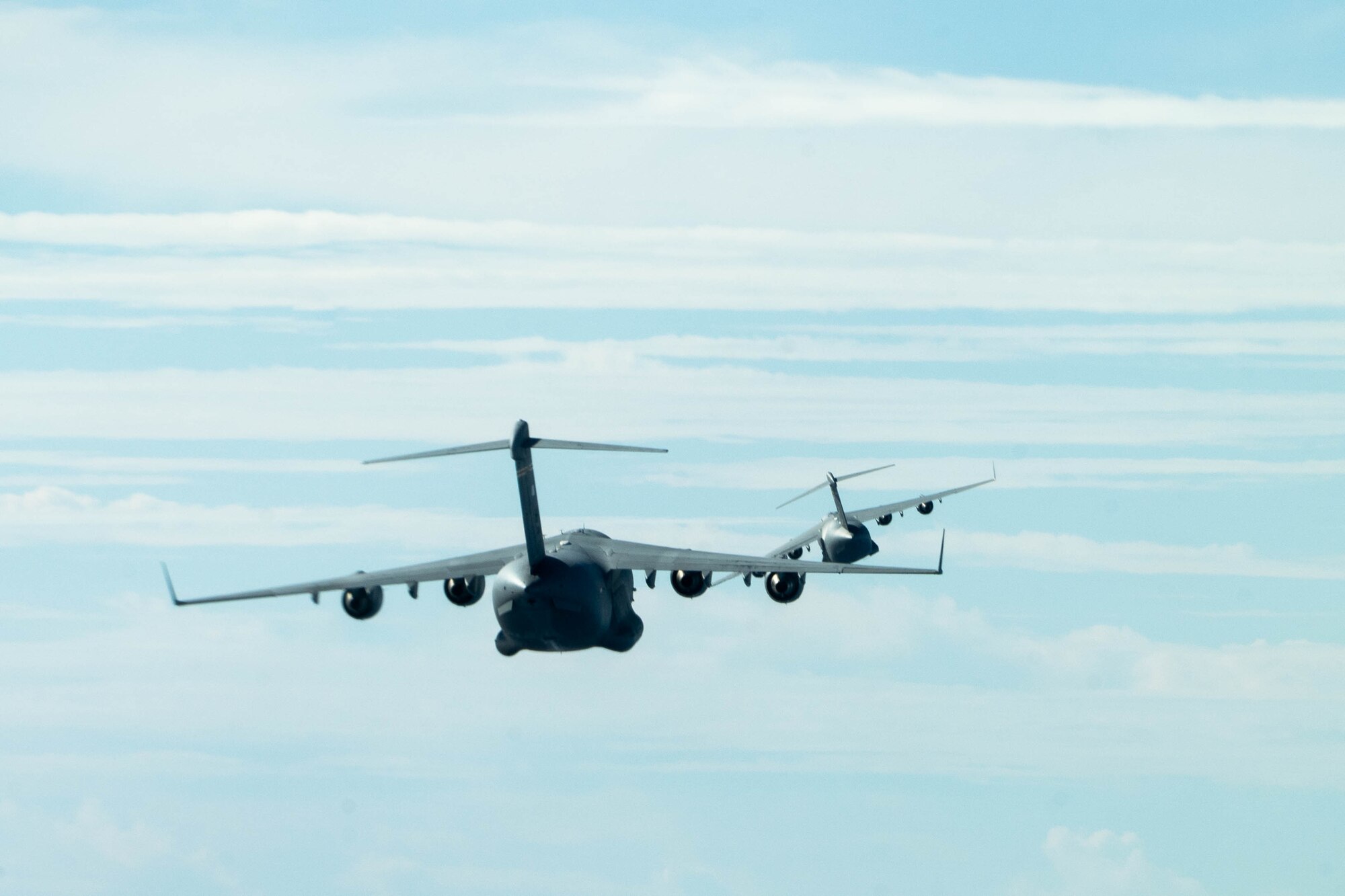 Two U.S. Air Force C-17 Globemaster III fly in formation during an aerial maneuver training mission around the Hawaiian islands as part of Joint Pacific Multinational Readiness Center (JPMRC) exercise 23-01, Nov. 5, 2022. The 15th Wing provides rapid global mobility and combat-ready across the Pacific. (U.S. Air Force photo by Senior Airman Makensie Cooper)