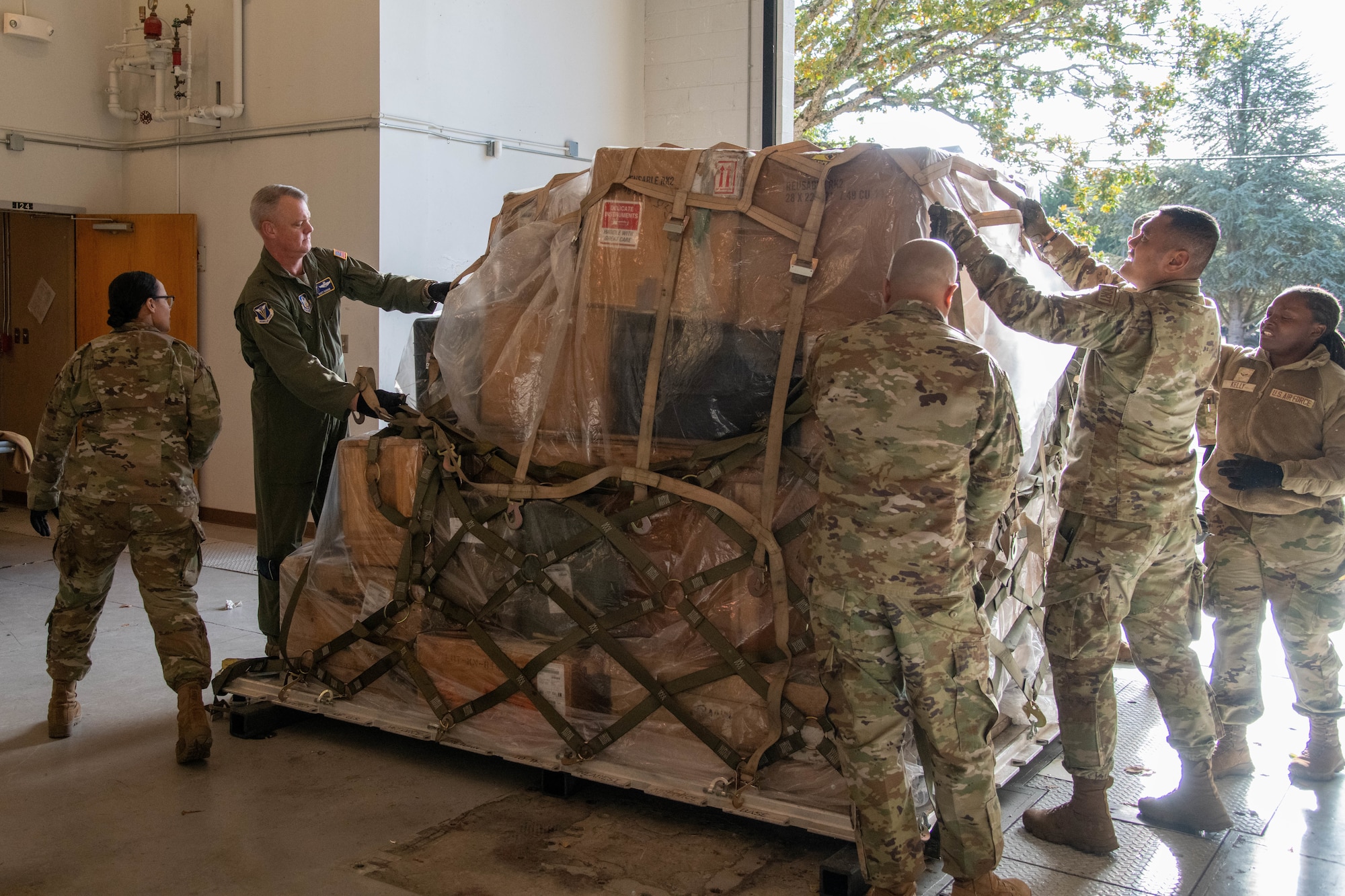 Airmen strap down items on a metal slab.