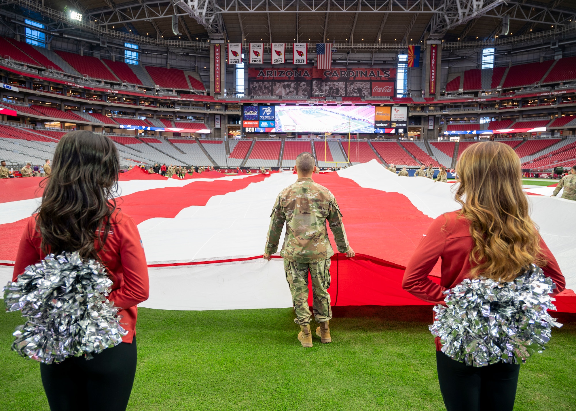 U.S. Air Force Airmen assigned to the 56th Fighter Wing, U.S. Army Soldiers from the Phoenix Recruiting Battalion, U.S. Marines and the Arizona Cardinals Cheerleaders practice unfurling the U.S. flag for the Salute to Service event Nov. 6, 2022, at State Farm Stadium, Glendale, Arizona.