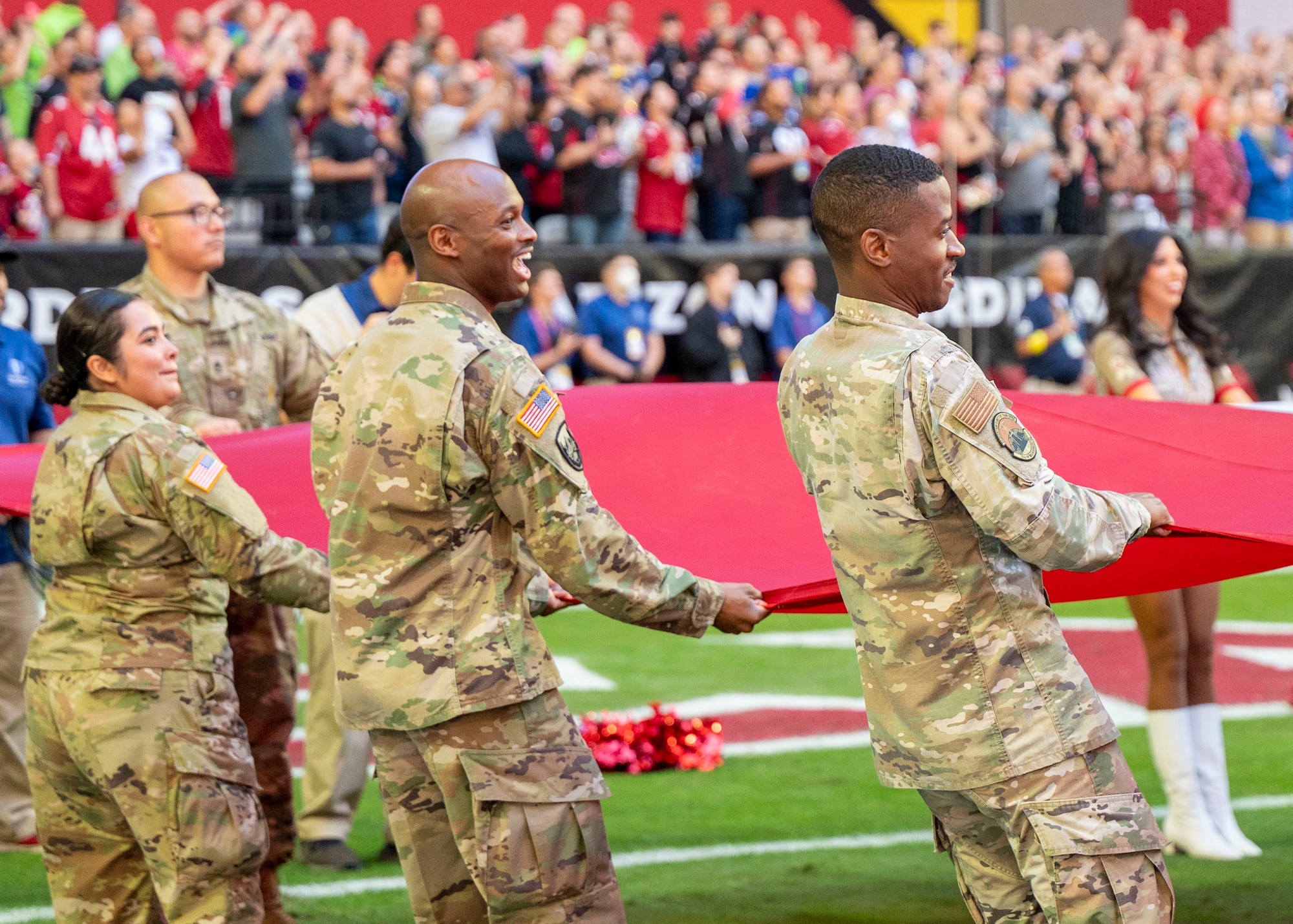 U.S. Air Force Airmen assigned to the 56th Fighter Wing and U.S. Army Soldiers from the Phoenix Recruiting Battalion unfurl the U.S. flag for the Arizona Cardinals Salute to Service event Nov. 6, 2022, at State Farm Stadium, Glendale, Arizona.