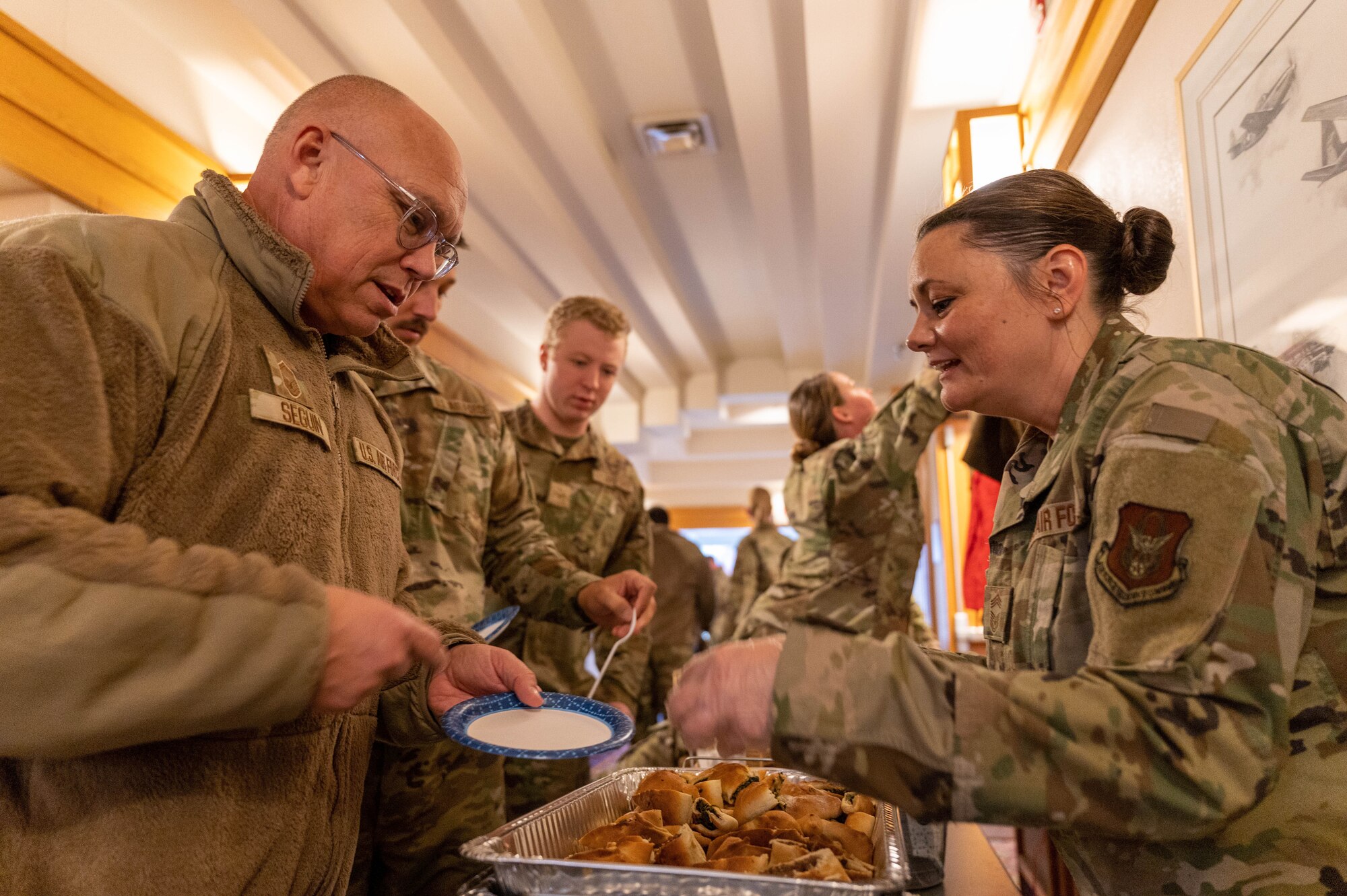 Senior Master Sgt. Chris Seguin, 934th Maintenance Squadron accessories flight chief, receives a Lebanese flatbread from Chief Master Sgt. Kristen Maloney, 934th Mission Support Group senior enlisted leader, during the 934th Airlift Wing’s Celebration of Nations at Minneapolis-Saint Paul Air Reserve Station, Minnesota, Nov. 5, 2022. This event provided Airmen an opportunity to try culturally different foods, listen to different music and look at different types of clothes.  (U.S. Air Force photo by Airman First Class Colten Tessness)