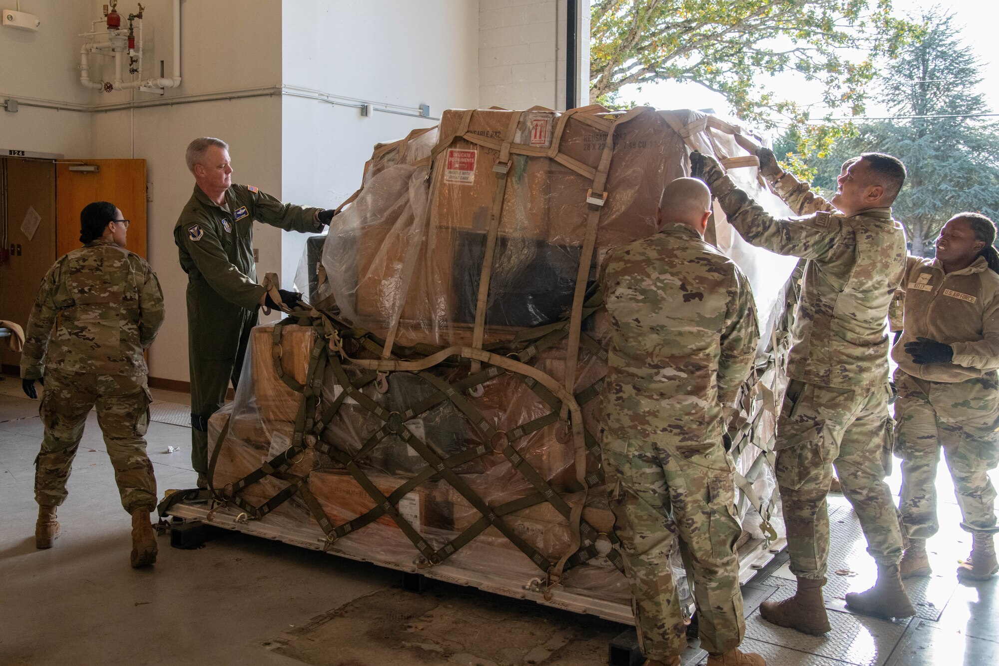 Airmen strap down items on a metal slab.