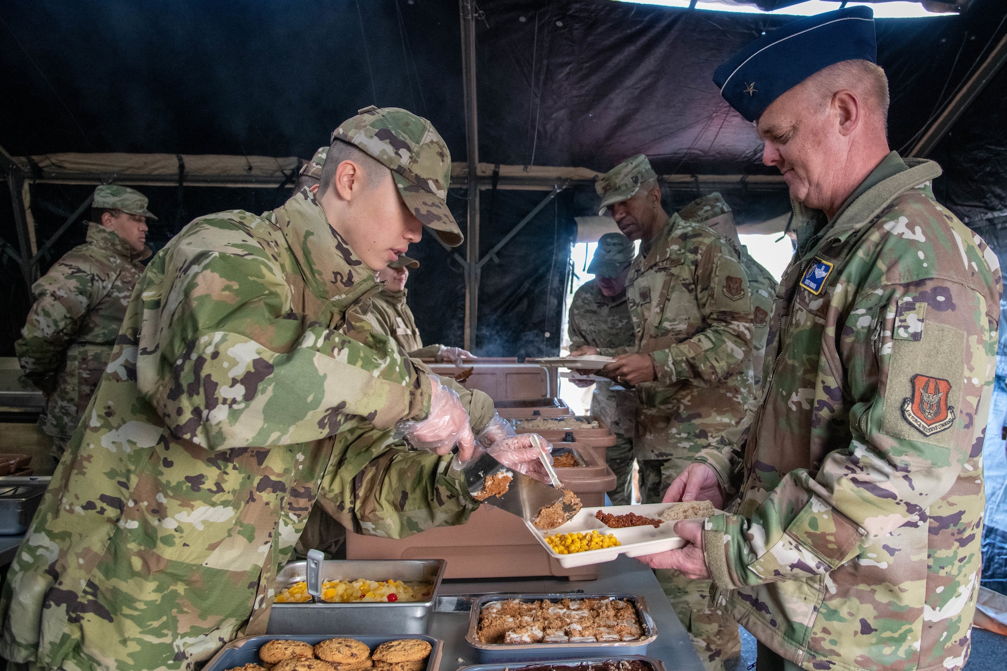 Airmen serve food in a tent.