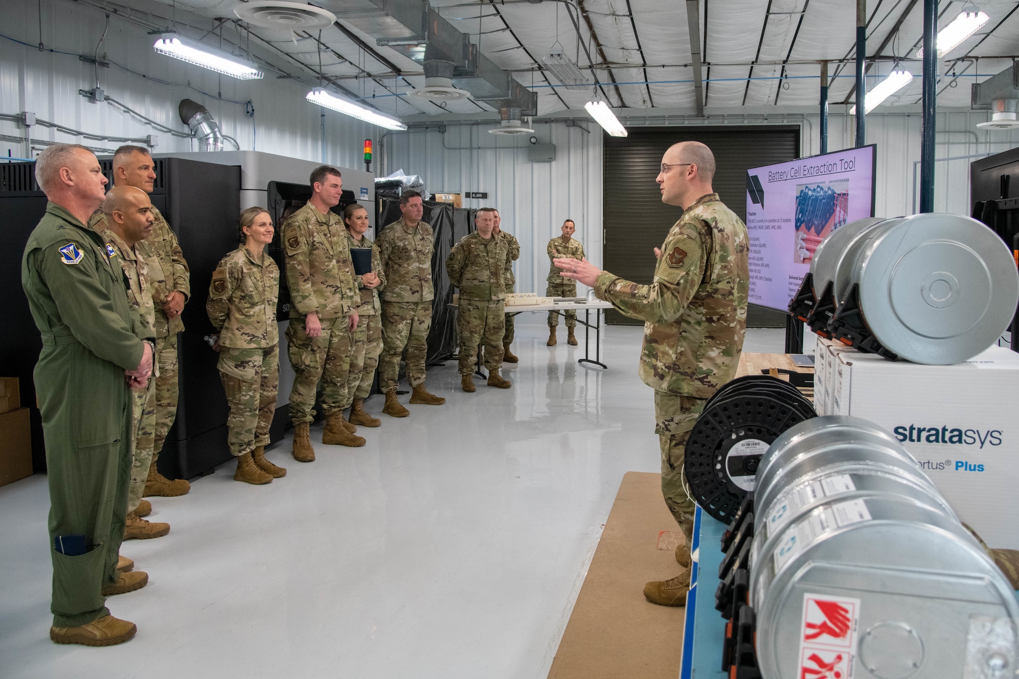 Surrounded by equipment, an Airman briefs leadership on technology.