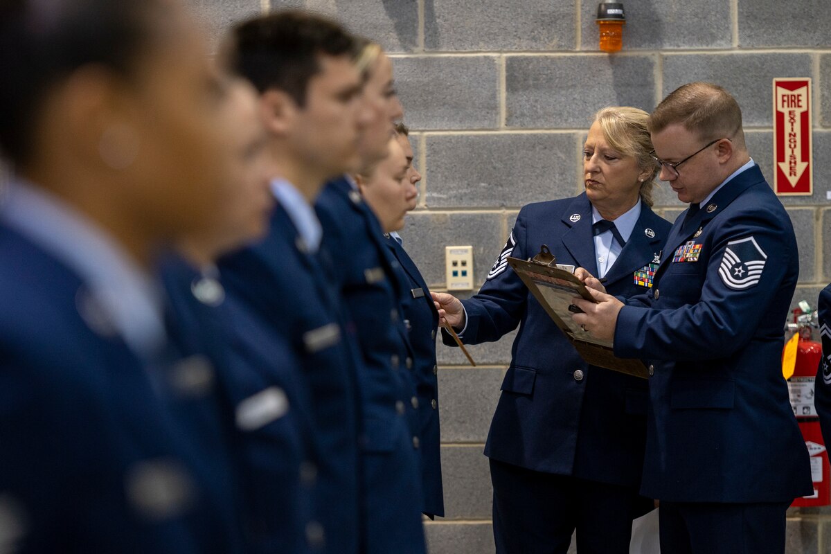 U.S. Air Force Master Sgt. Shannon Fairburn and Master Sgt. Lewis Staubs ensure Airmen in the 167th Materiel Management Flight are wearing their service dress uniforms in accordance with dress and appearance standards during a uniform inspection, Nov. 6, 2022, at the 167th Airlift Wing, Shepherd Field, Martinsburg, West Virginia