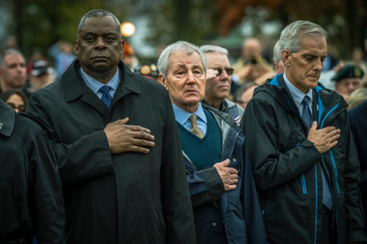 Several men stand with their hand over their heart.