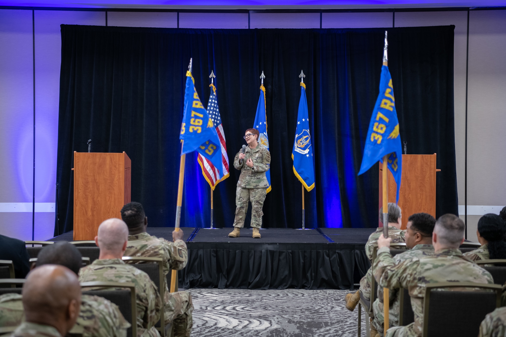 Chief Master Sgt. Jeanette Masters stands on a stage in front of recruiters and leadership