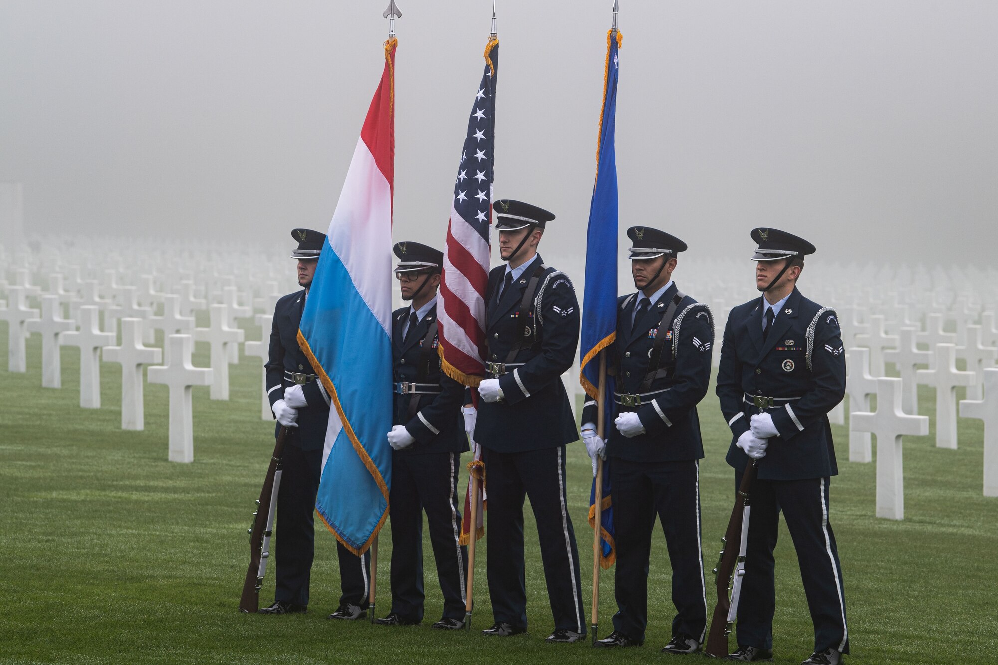 Honor guard members from Spangdahlem Air Base stand in front of the cemetery after performing a detail