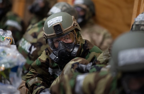 Person in gas mask and other protective gear crouches down