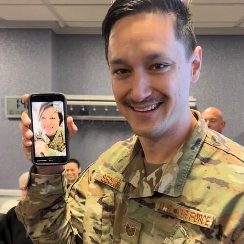 Man in uniform poses with phone during a video call
